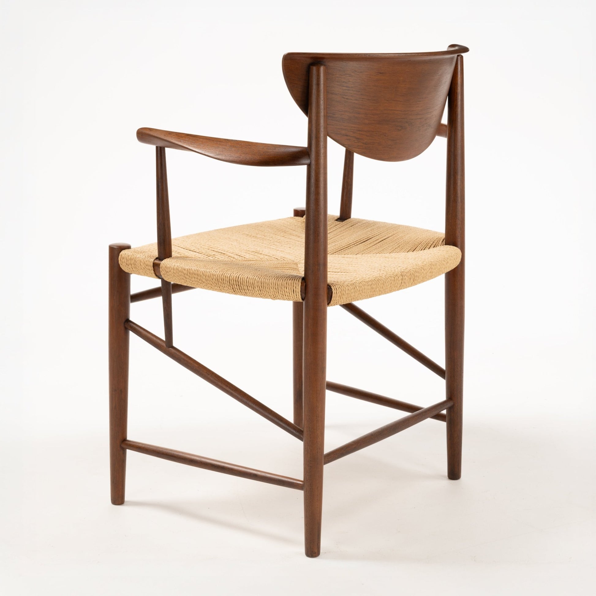 Rear angle of Hvidt & Molgaard Model 317 chair showing curved teak backrest and woven  fiber seat on tapered wood frame