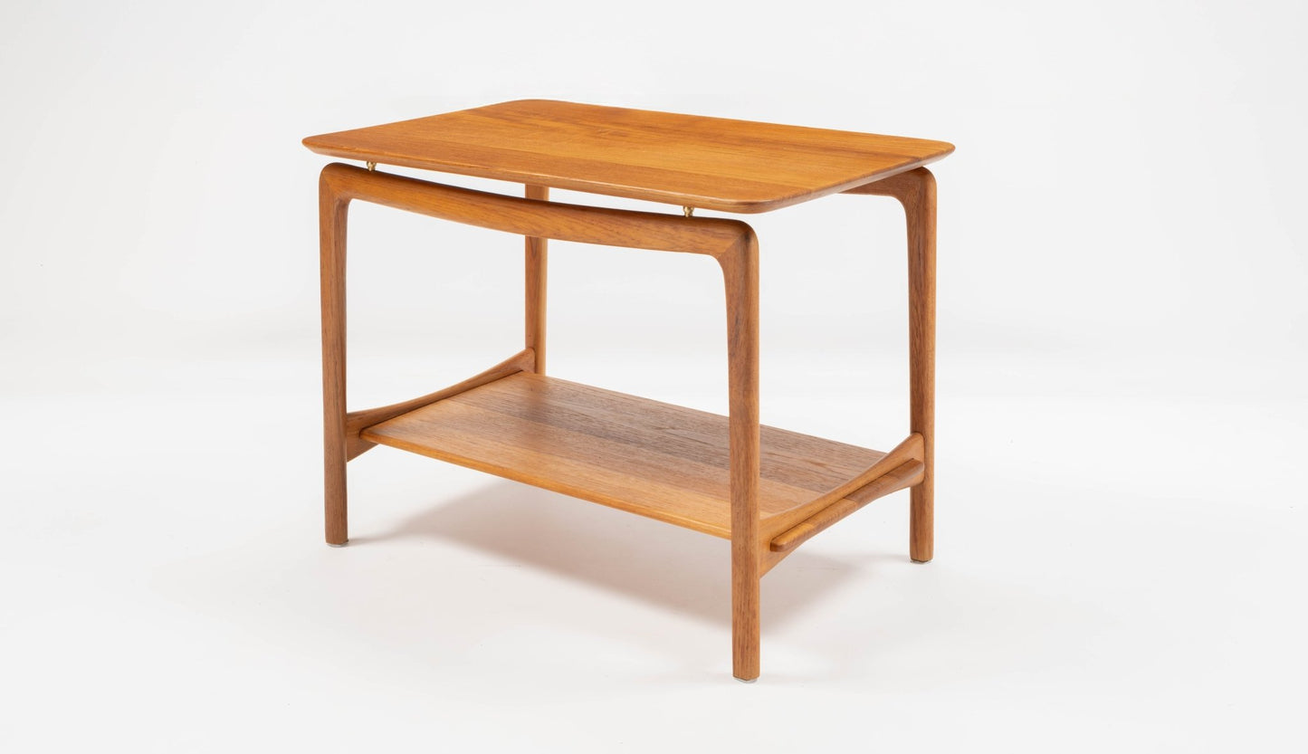 Mid-century modern Danish teak side table with rounded corners, sculpted legs, and lower shelf on white background.