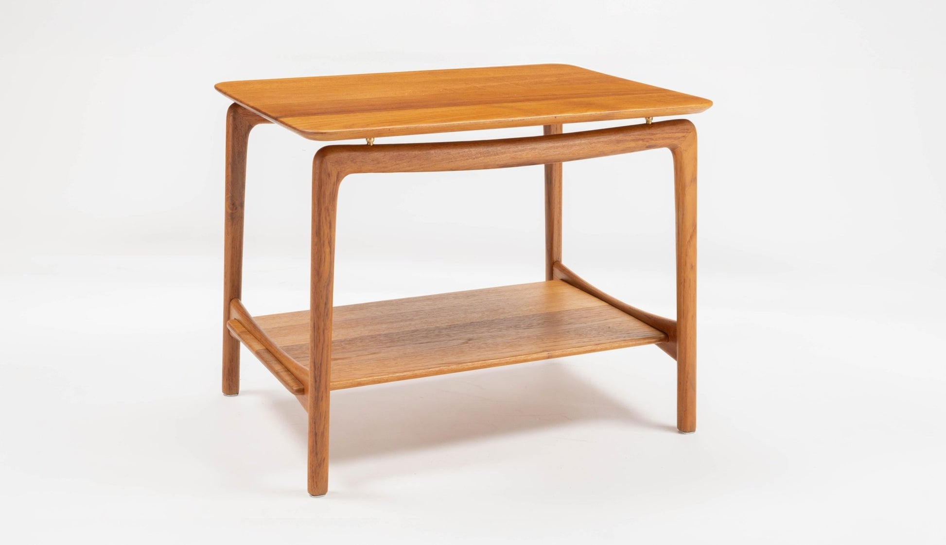 Mid-century modern teak side table by Hvidt & Molgaard with sculpted legs and lower shelf on white background