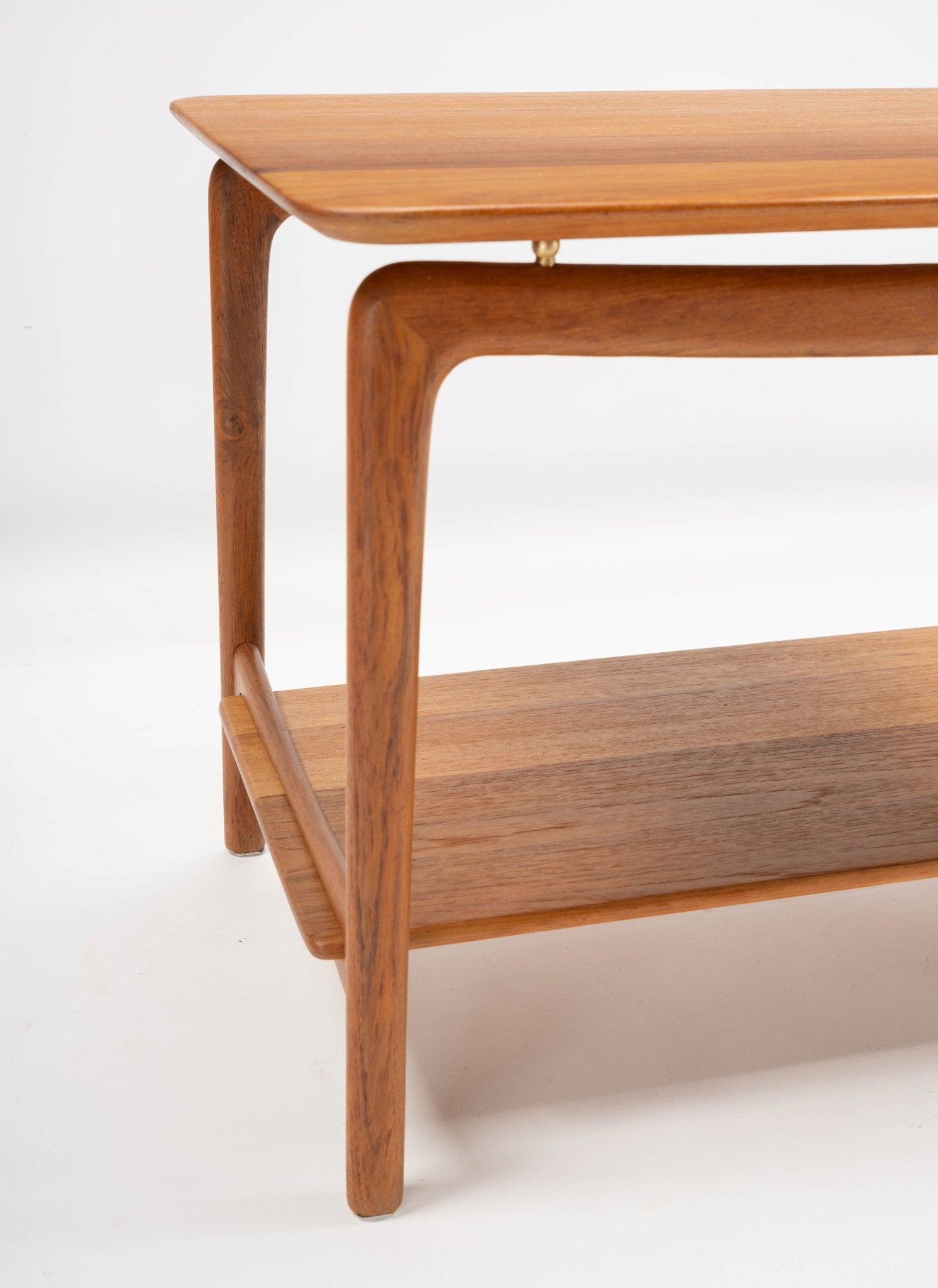 Mid-century modern teak side table designed by Hvidt & Mølgaard with brass spacers and sculpted legs on white background
