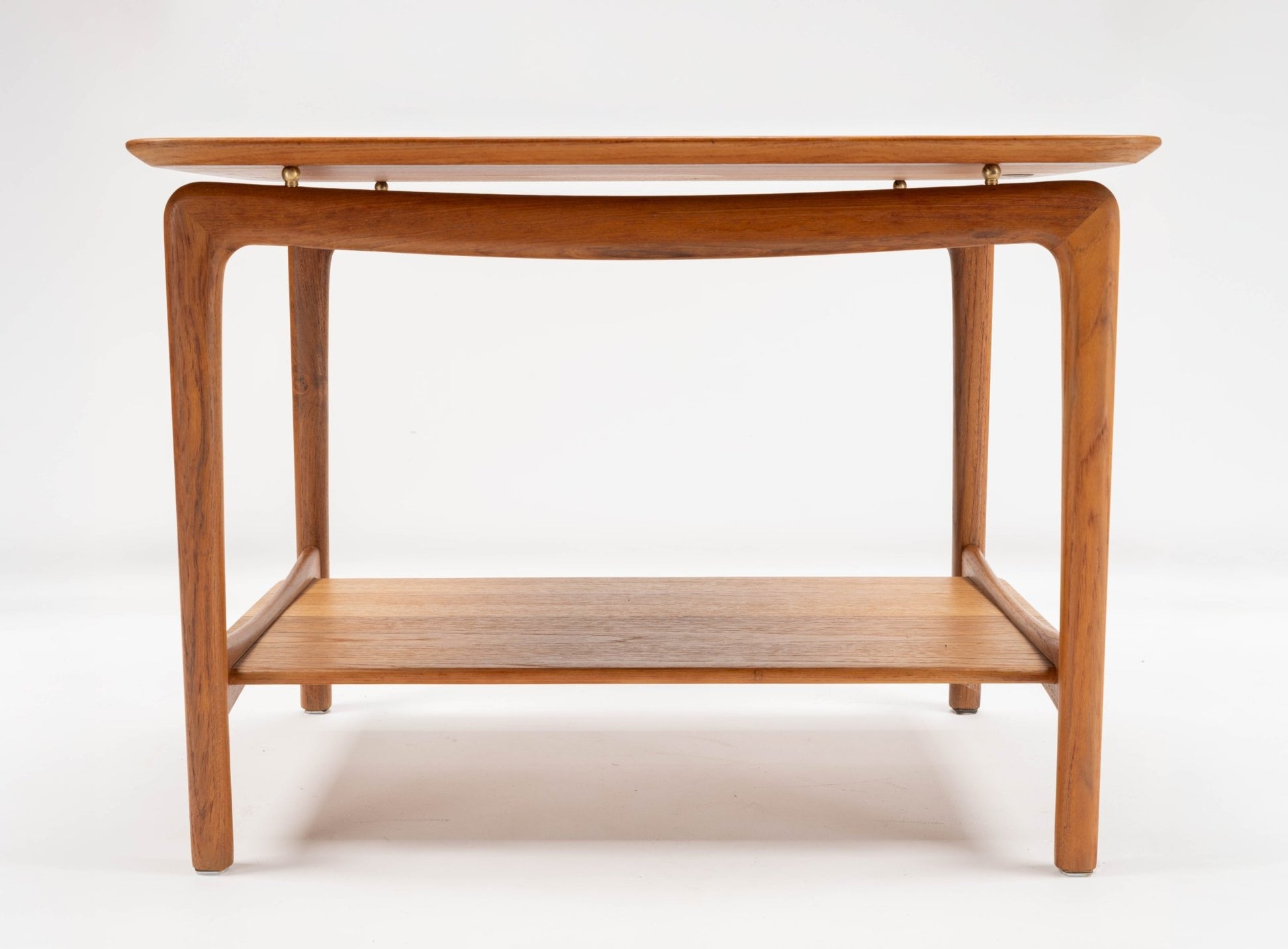 1950s Danish teak side table by Hvidt & Molgaard with sculpted legs and brass spacers on white background
