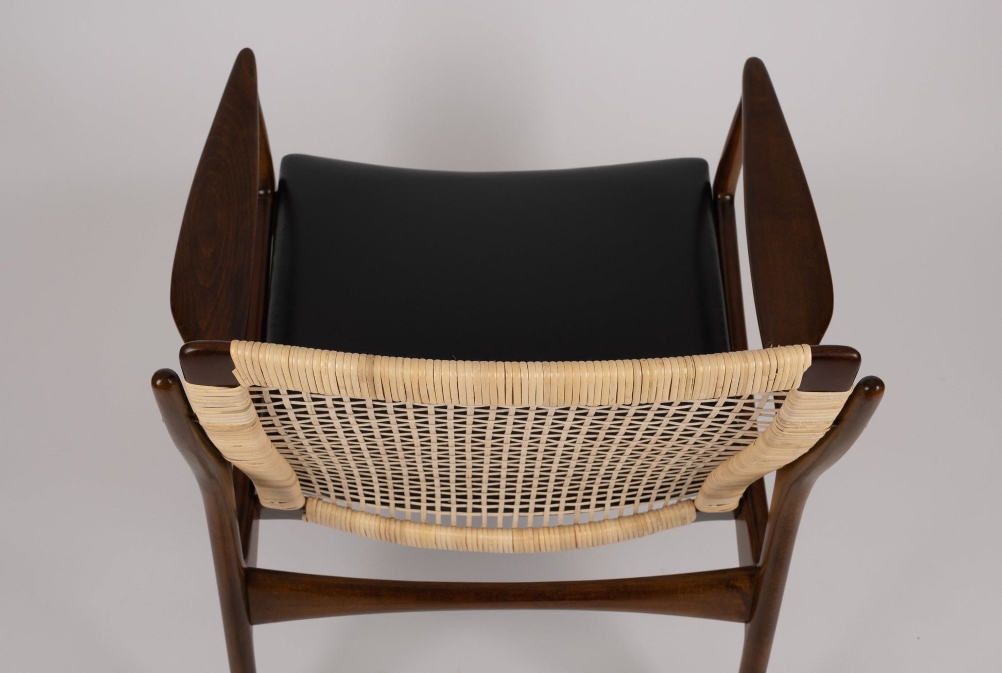 Top view of Ib Kofod Larsen model 18-15 cane armchair with teak frame and original black faux leather seat
