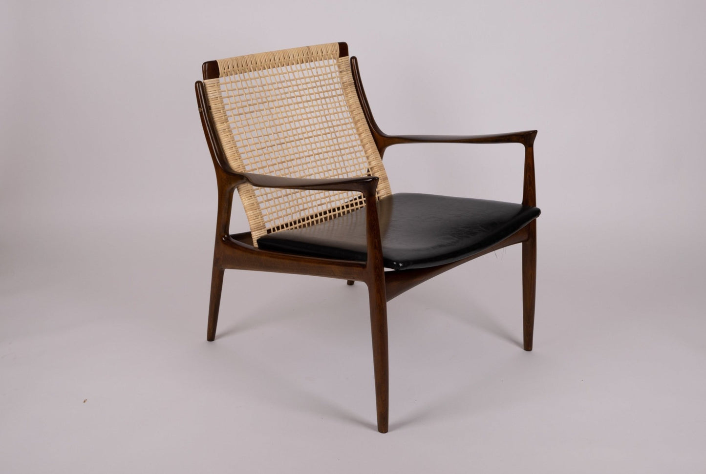Ib Kofod Larsen model 18-15 cane armchair with teak frame and original black faux leather seat from 1960s Denmark