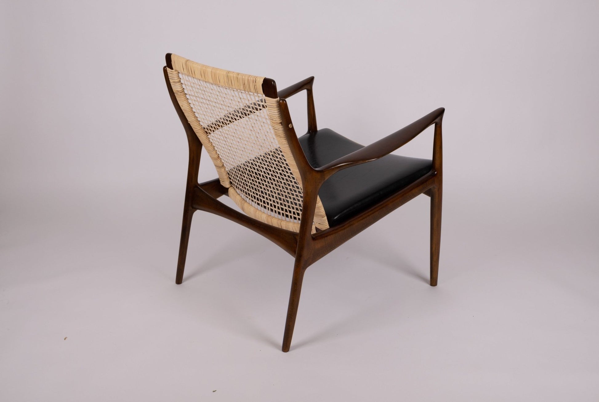 Ib Kofod Larsen model 18-15 cane armchair with teak frame and original black faux leather seat from 1960s Denmark.