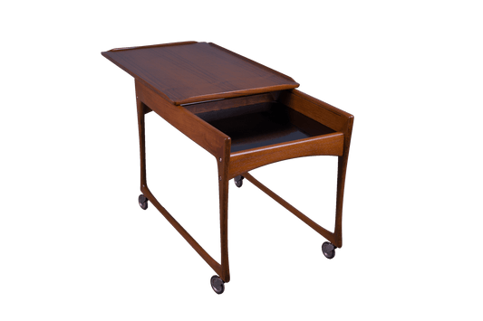 Mid-century modern Ingvar Jensen teak bar cart with sliding top, black laminate storage compartment, and rolling casters.