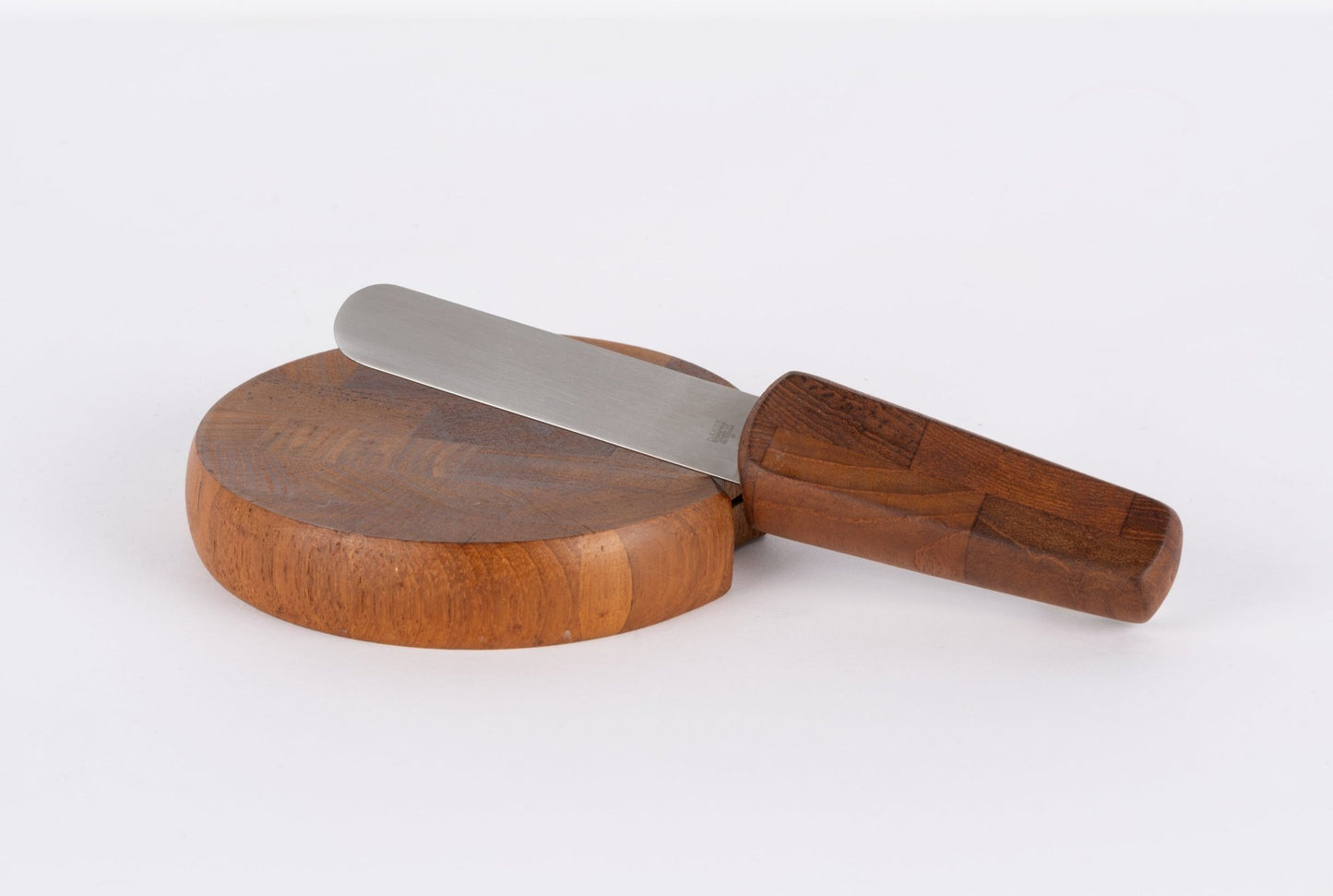 Jens Quistgaard mid-century modern teak cutting board with matching wooden-handled cheese knife on white background.