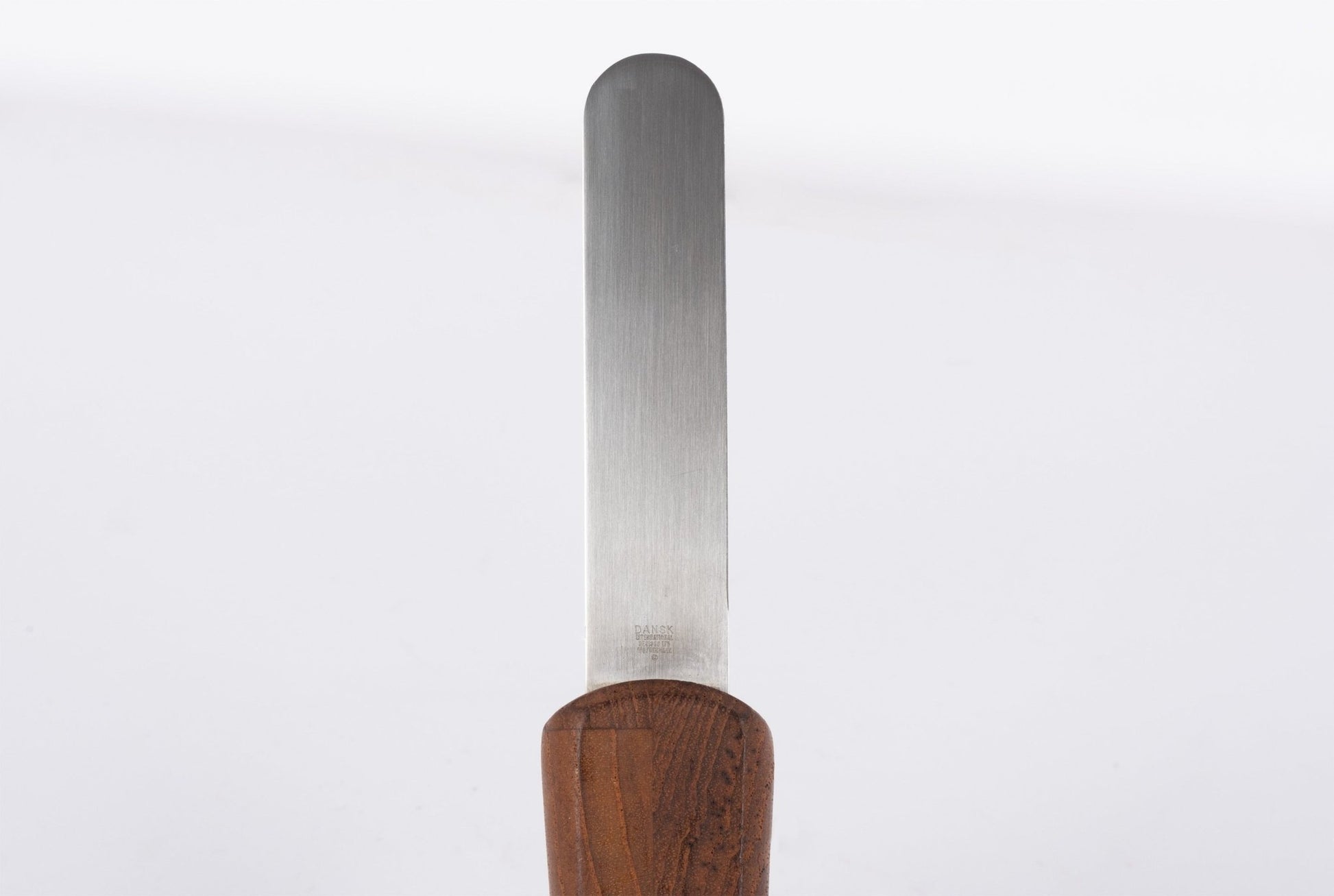Mid-century modern cheese knife with stainless steel blade and solid teak wood handle on white background