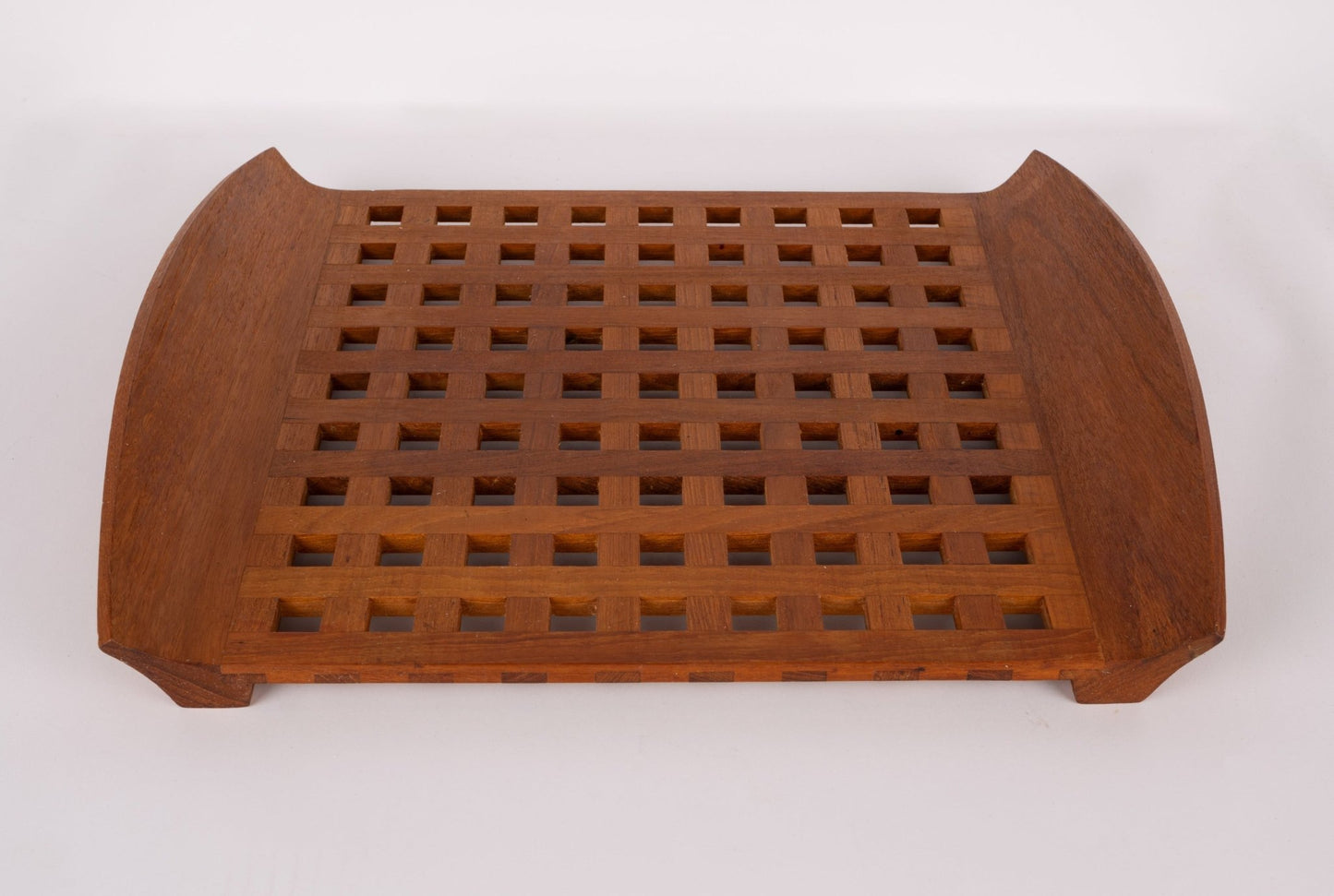Mid-century modern Jens Quistgaard teak lattice serving tray with curved edges and square cutout pattern.