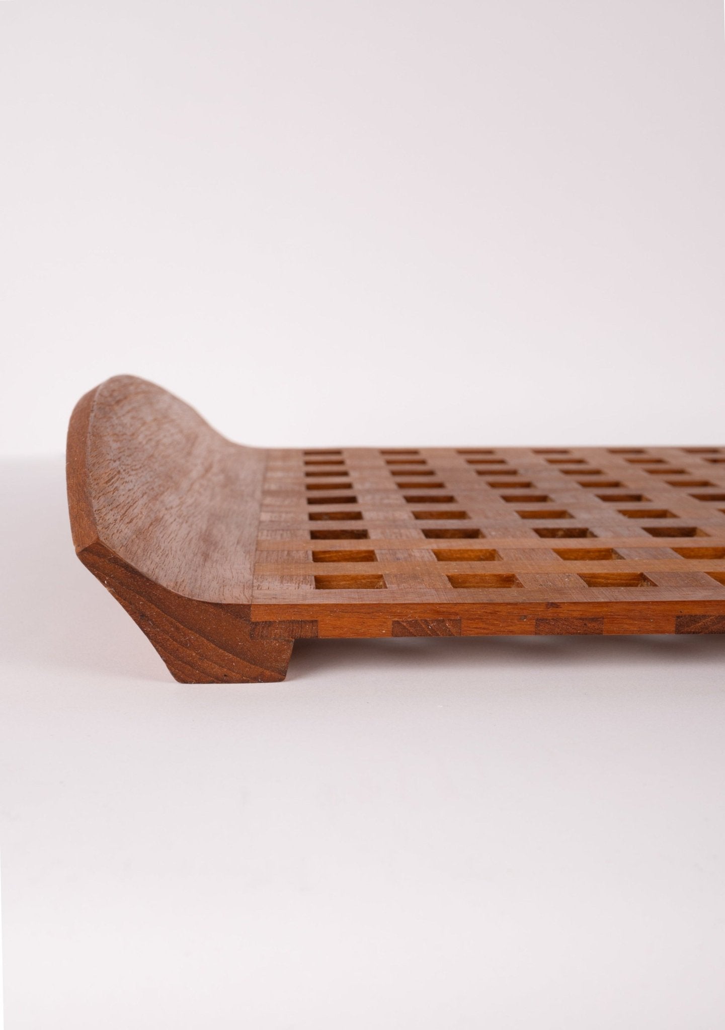 Mid-century modern teak lattice serving tray by Jens Quistgaard with curved handles and square cutout design.