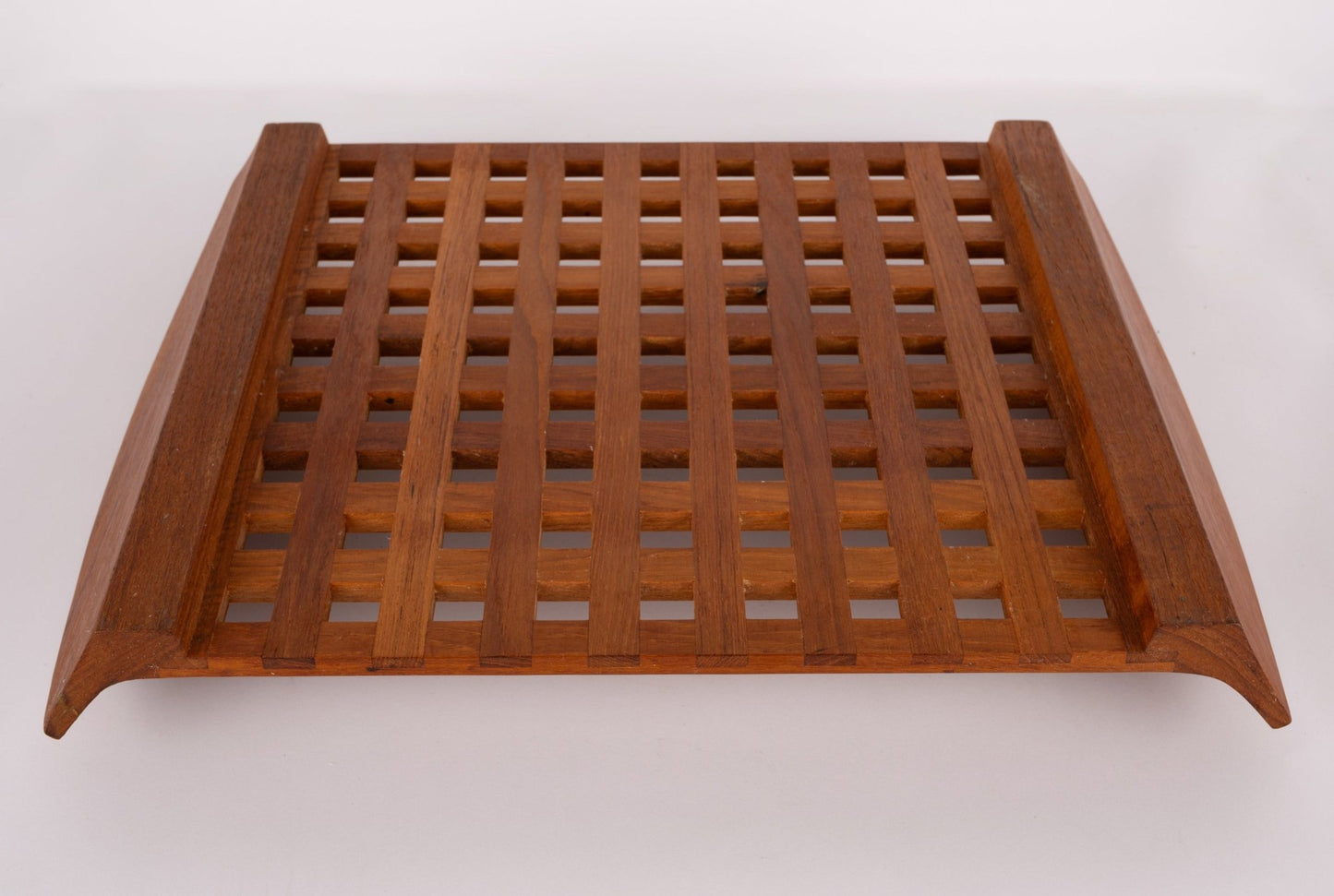 Jens Quistgaard teak lattice serving tray with geometric grid design and curved edges, mid-century Danish modern style.