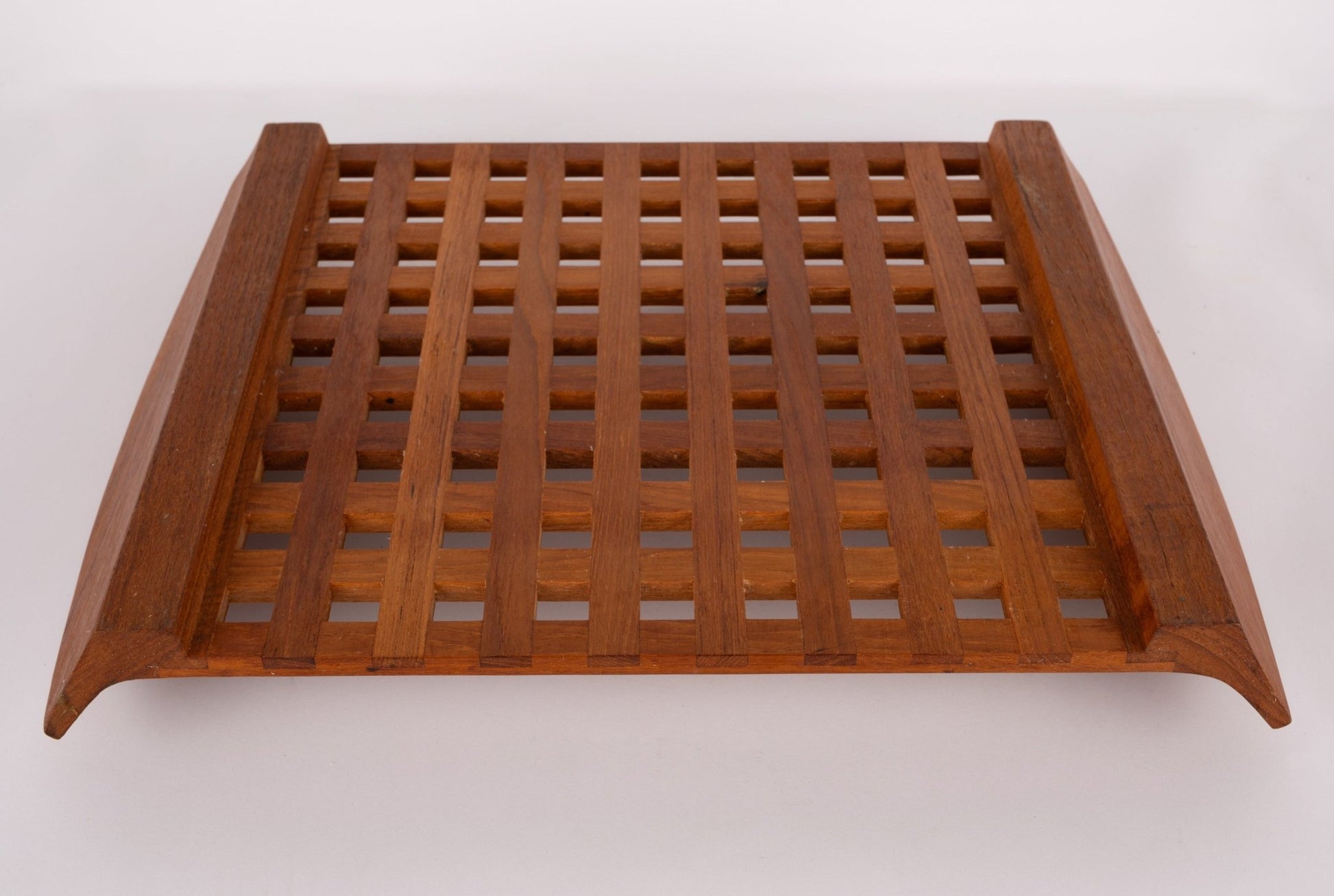 Jens Quistgaard teak lattice serving tray with geometric grid design and curved edges, mid-century Danish modern style.