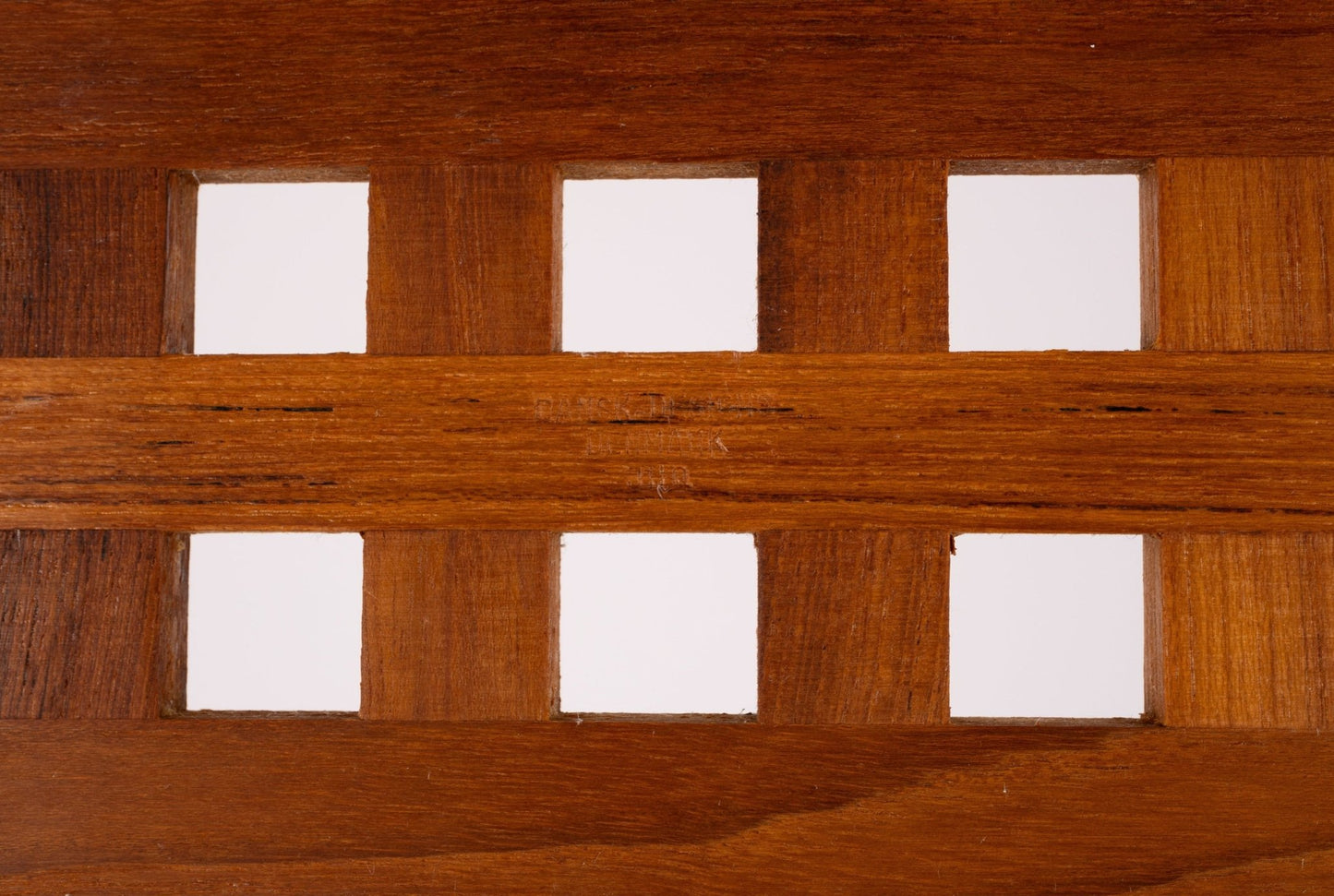 Close-up of Jens Quistgaard teak lattice serving tray showing rectangular cutouts and rich wood grain detail
