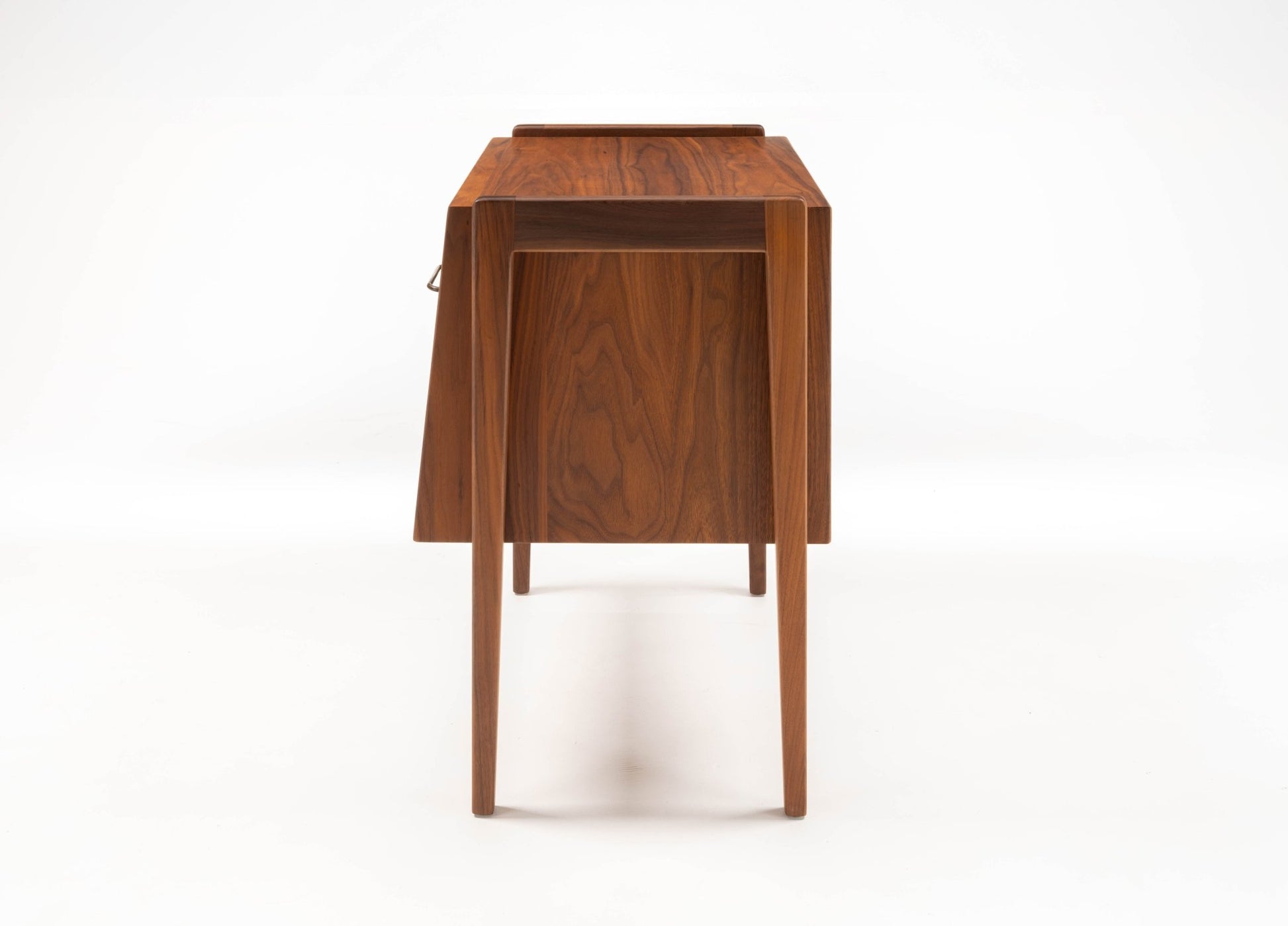 Pair of mid-century modern walnut bedside tables with tapered legs and storage compartments on white background