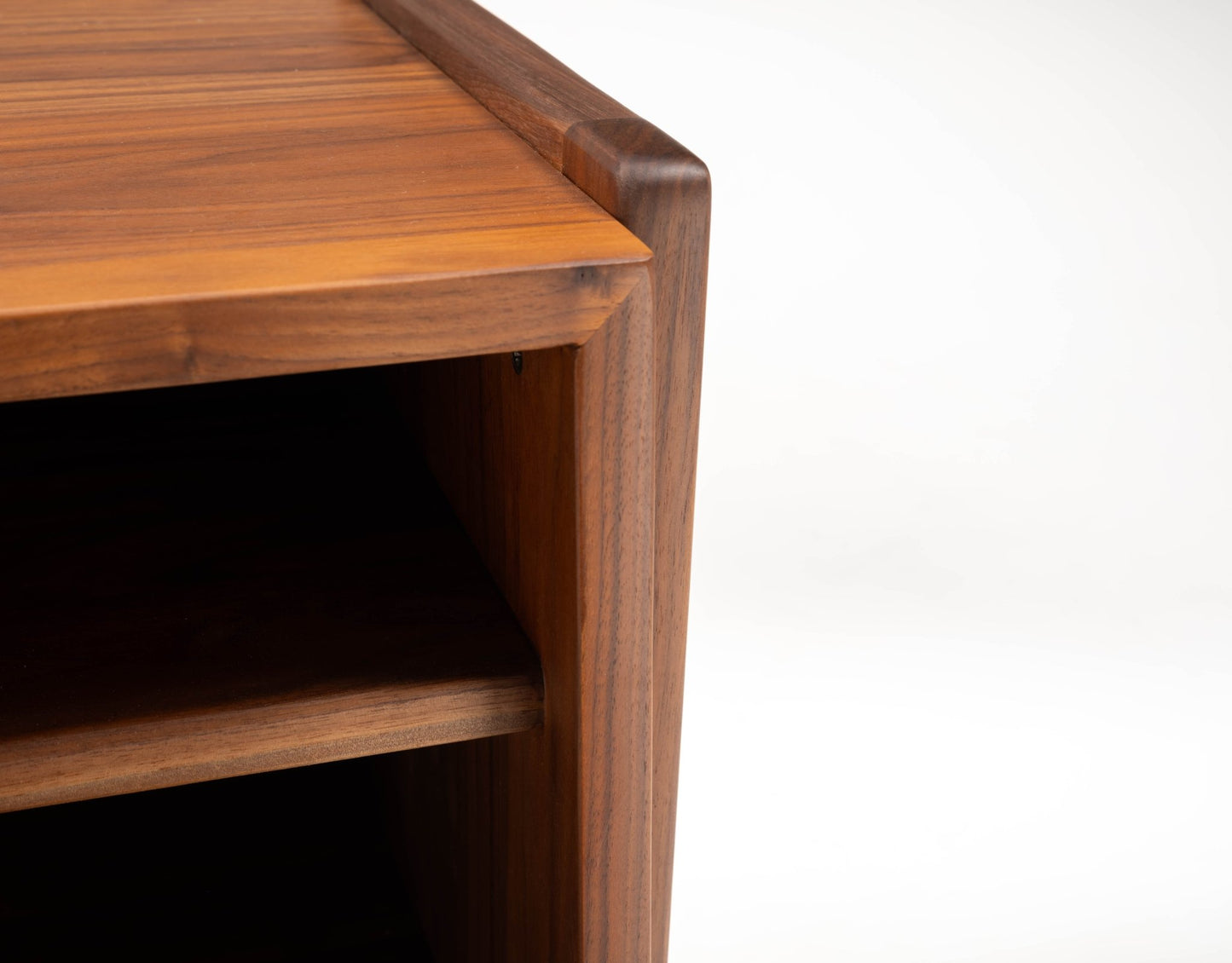 Close-up of mid-century modern Jens Risom walnut bedside table corner showing open shelf and wood grain detail