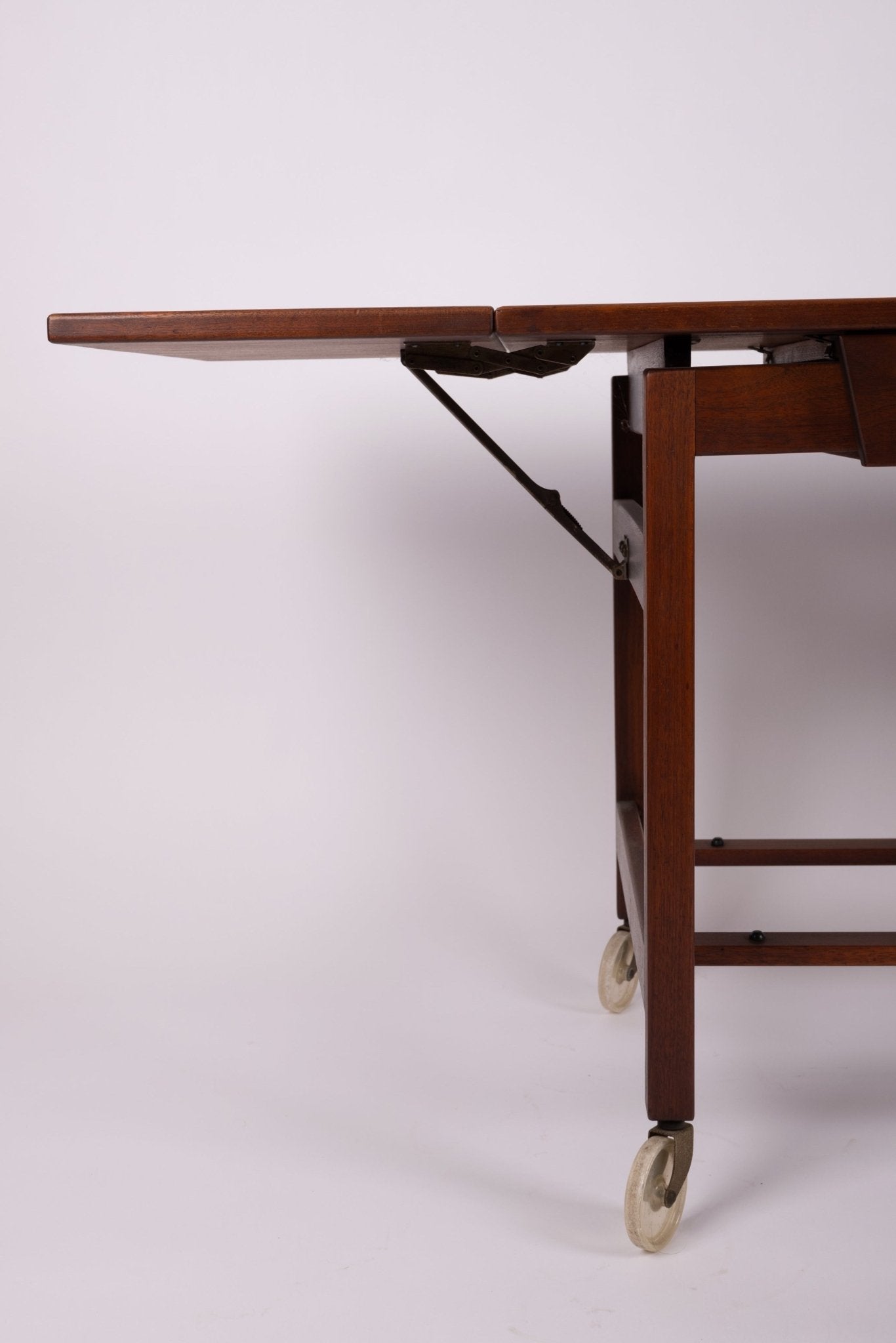 Close-up of side leaf mechanism on Jens Risom expandable serving cart with wooden frame and caster wheels from the 1960s