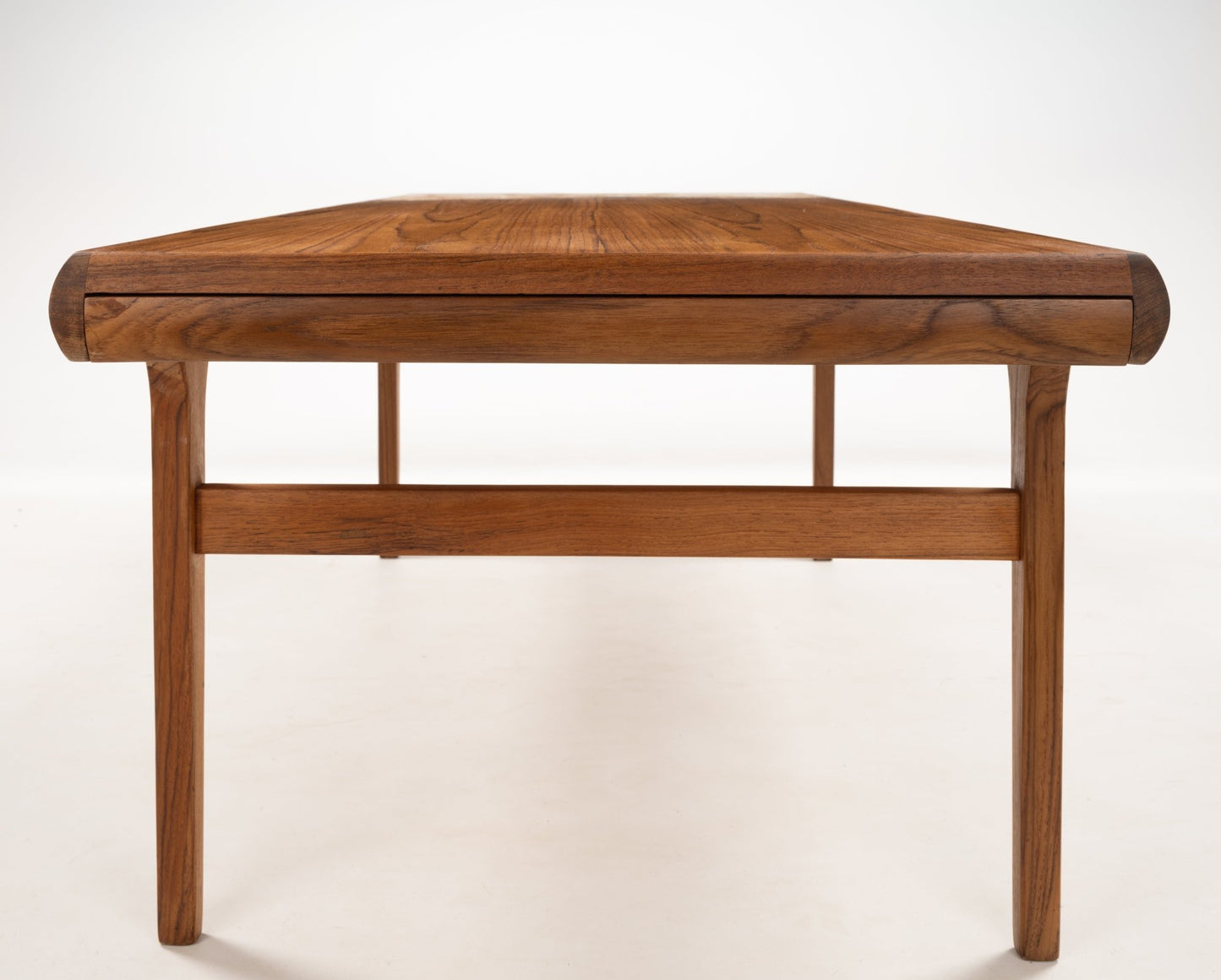 Straight-on view of Johannes Andersen teak coffee table highlighting clean lines and softly curved edges in Danish style