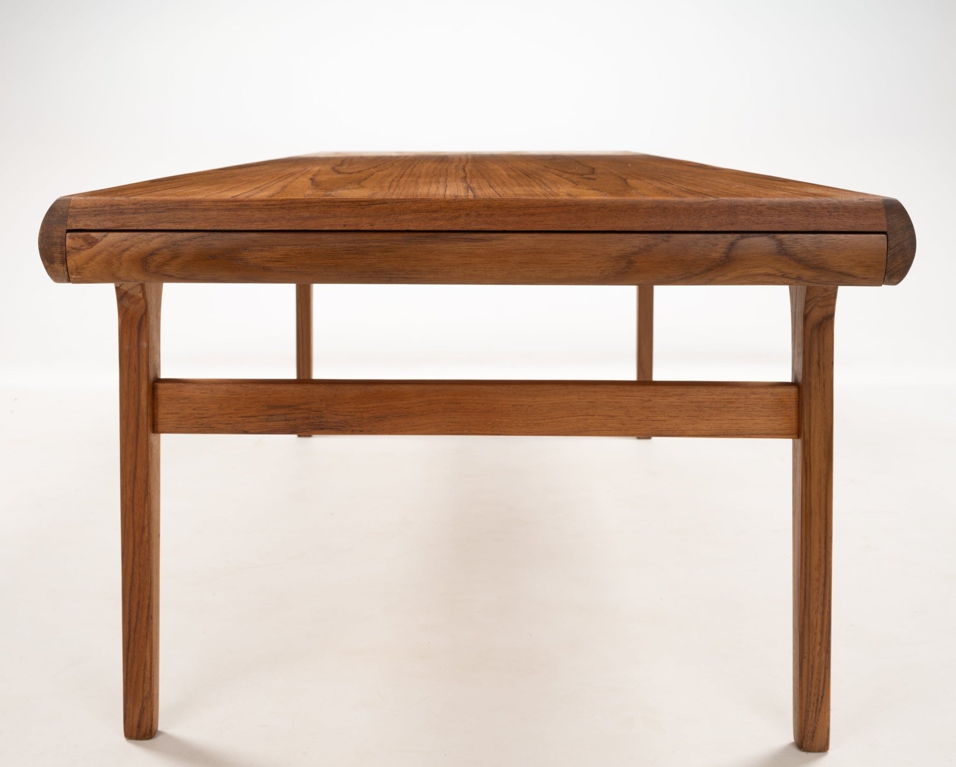 Straight-on view of Johannes Andersen teak coffee table highlighting clean lines and softly curved edges in Danish style