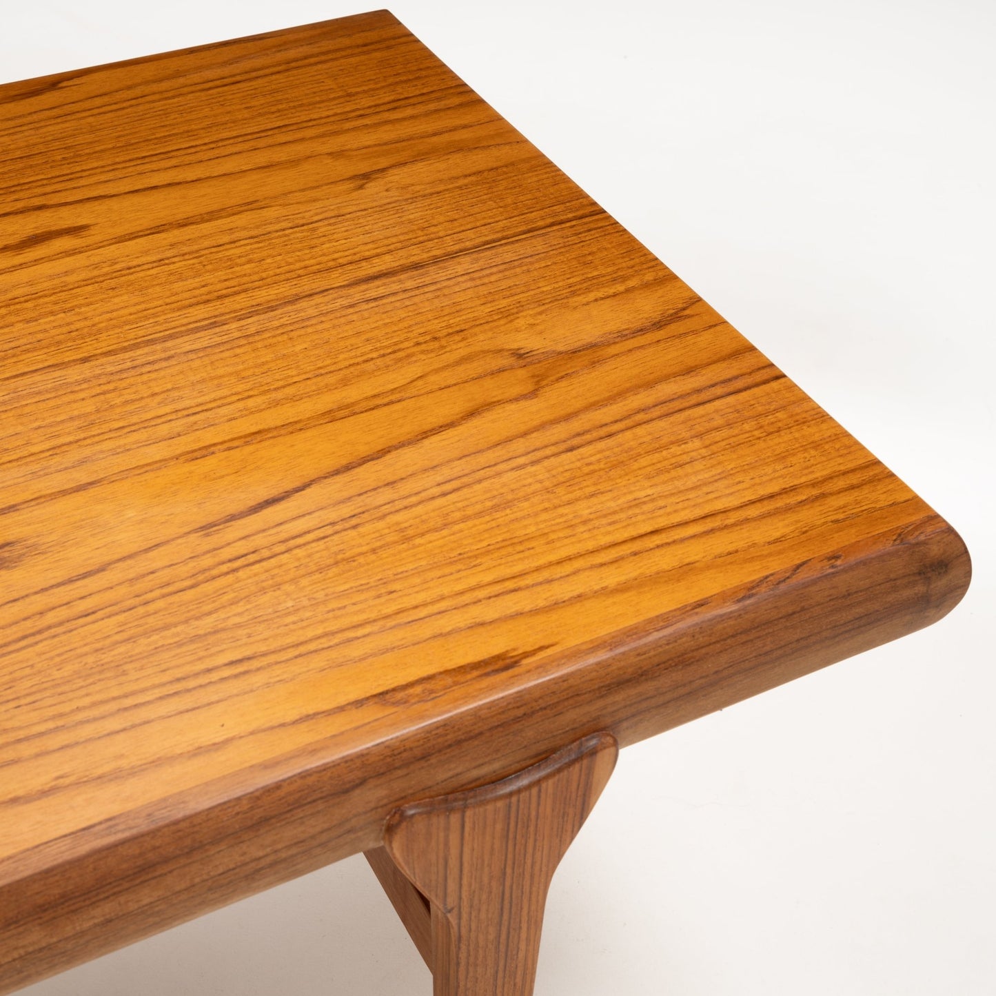 Close-up of Johannes Andersen teak coffee table corner with smooth rounded edge and rich wood grain finish