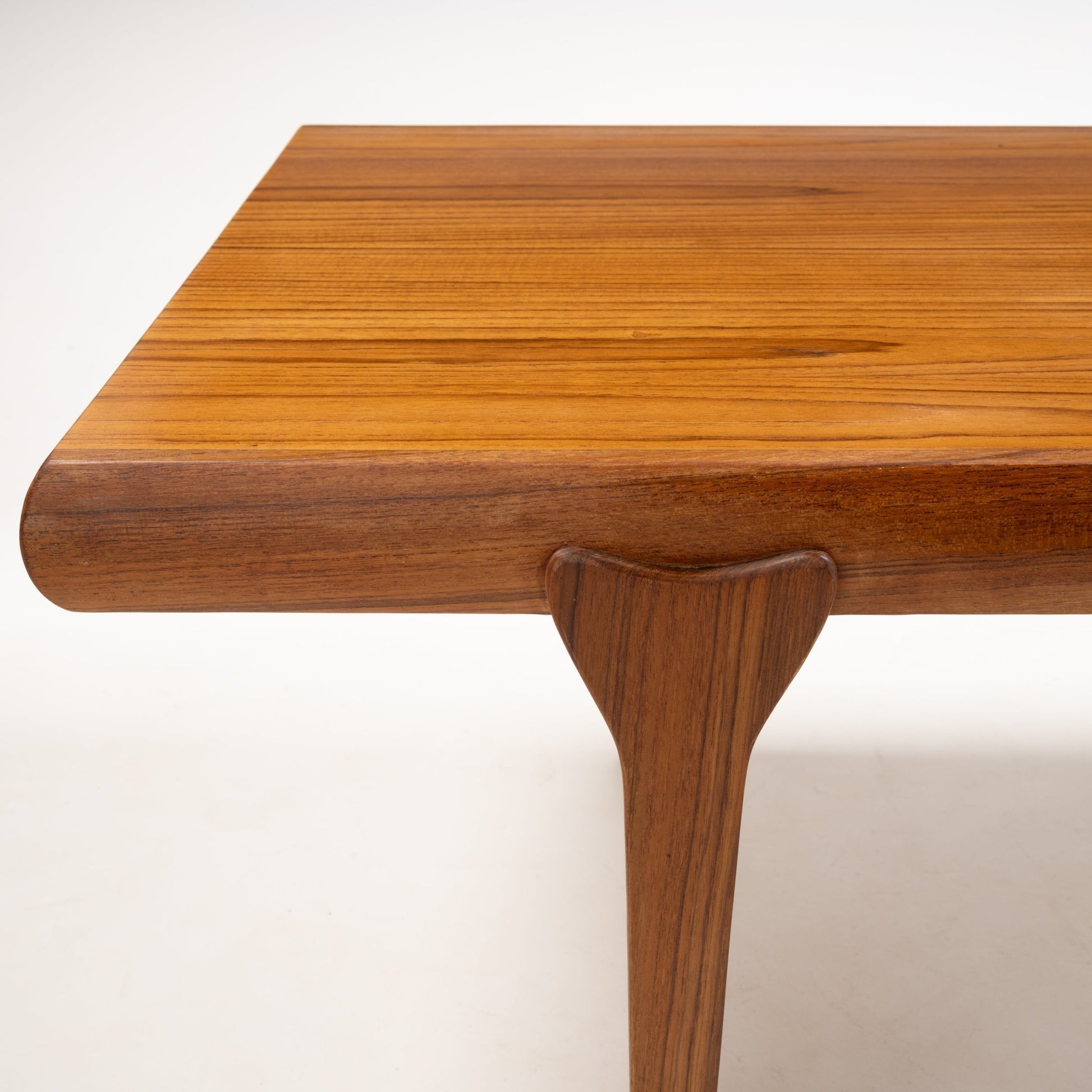 Close-up of teak coffee table corner showing smoothly rounded edge and tapered leg in Danish mid-century modern style