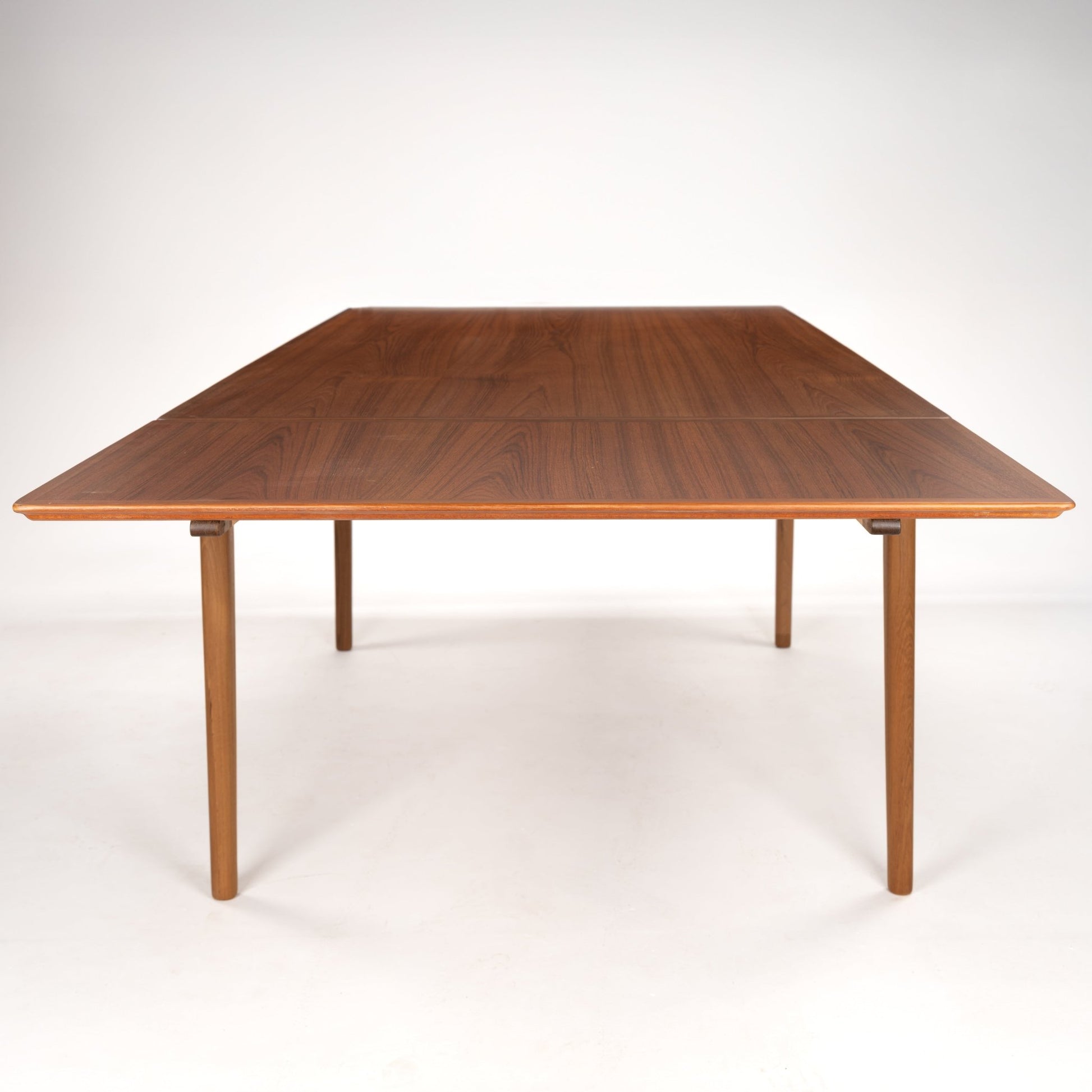 Rectangular wooden dining table with warm wood grain finish and straight tapered legs on a white background