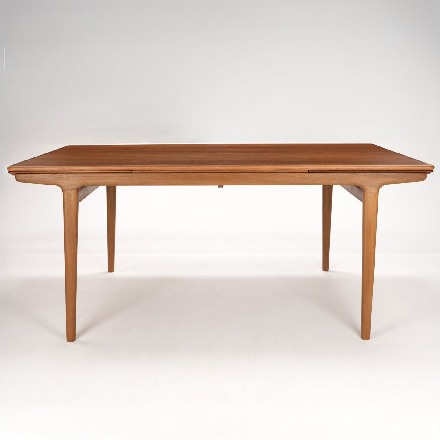 Rectangular wooden dining table with smooth rounded edges and slender tapered legs in a light brown finish
