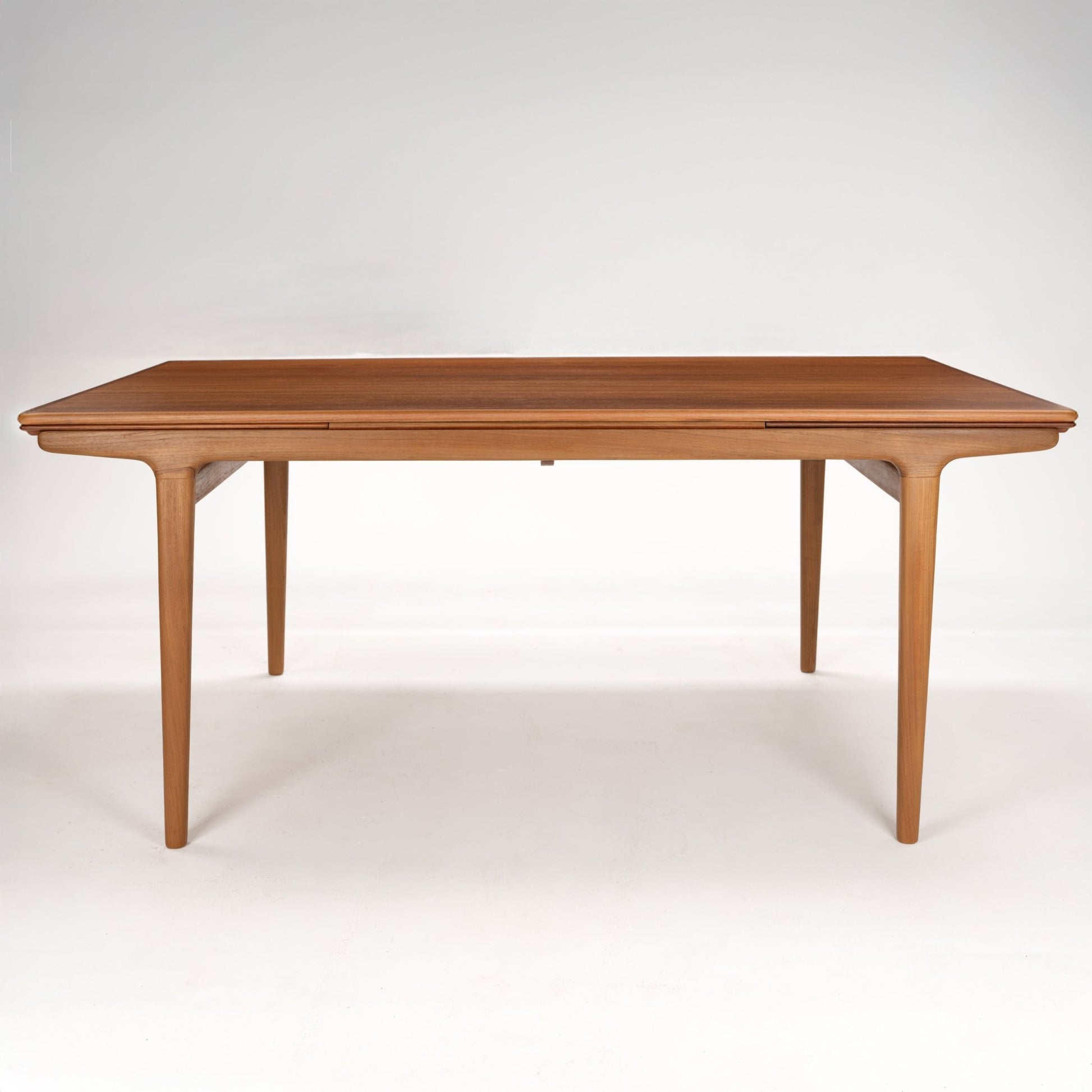 Rectangular wooden dining table with smooth rounded edges and slender tapered legs in a light brown finish
