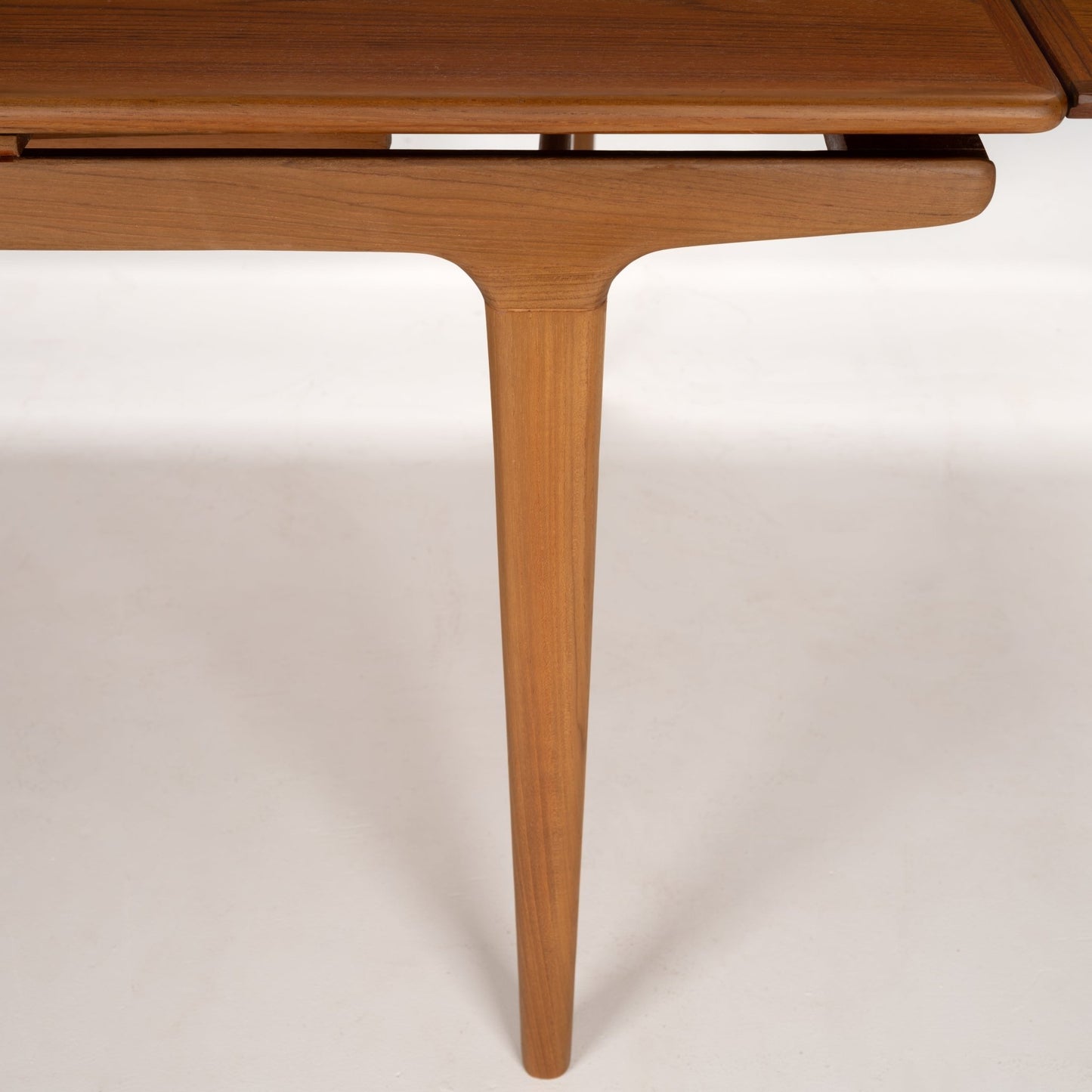 Close-up of tapered wooden table leg with smooth finish and subtle grain in a warm natural wood tone