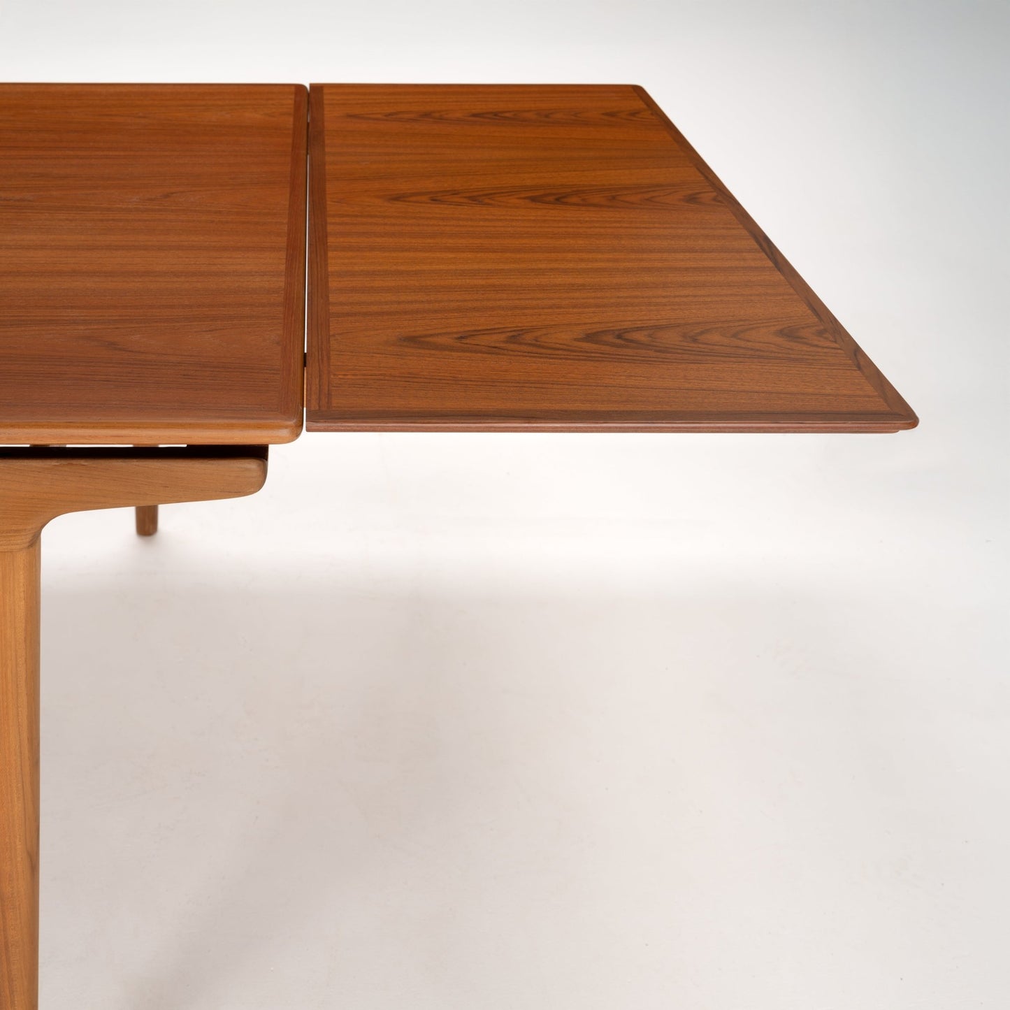 Extendable wooden table leaf with rich grain pattern and smooth rounded edges in a medium brown finish