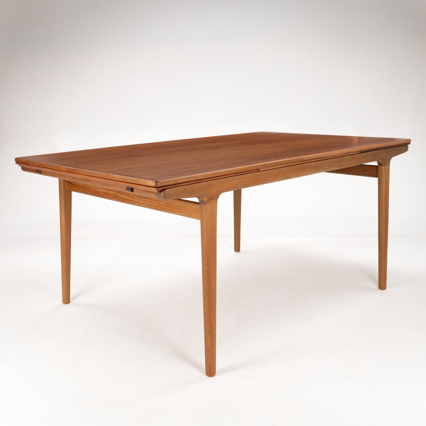 Rectangular mid-century wooden table with slightly rounded edges and tapered legs in a light walnut finish