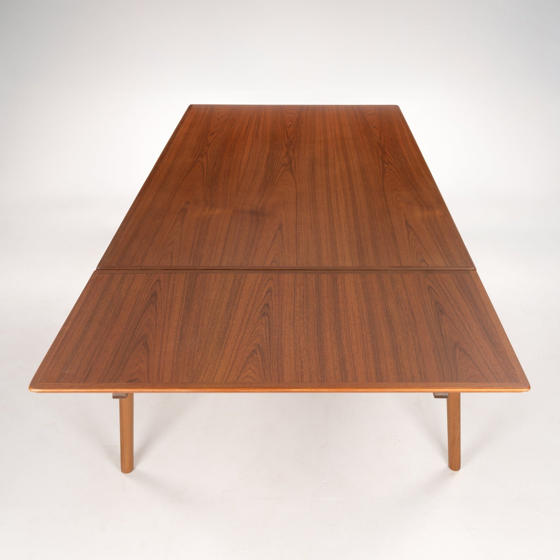 Extendable rectangular wooden table with fine grain pattern and slender tapered legs in a warm brown finish