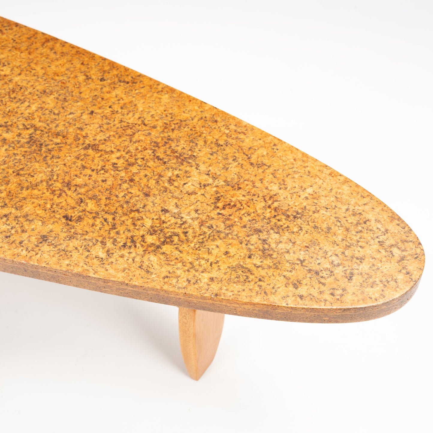 John Keal 'Outrigger' Coffee Table showing a close-up of the tapered cork tabletop with its rich, mottled texture resting on a sculptural wooden leg, highlighting mid century modern furniture.