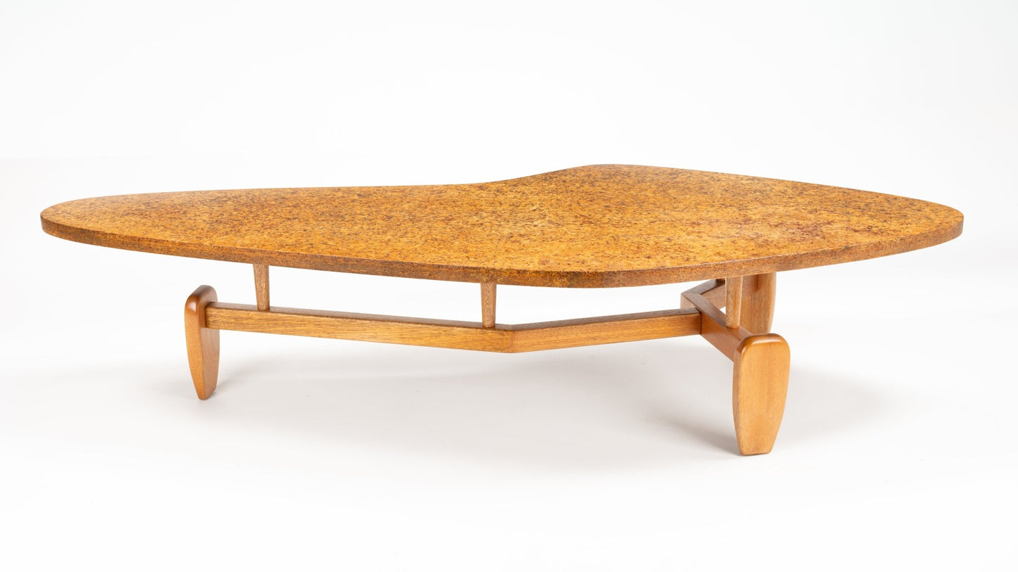 John Keal 'Outrigger' Coffee Table with a gently curved cork surface and a wooden base featuring rounded legs connected by a smooth stretcher, illustrating mid century modern furniture.