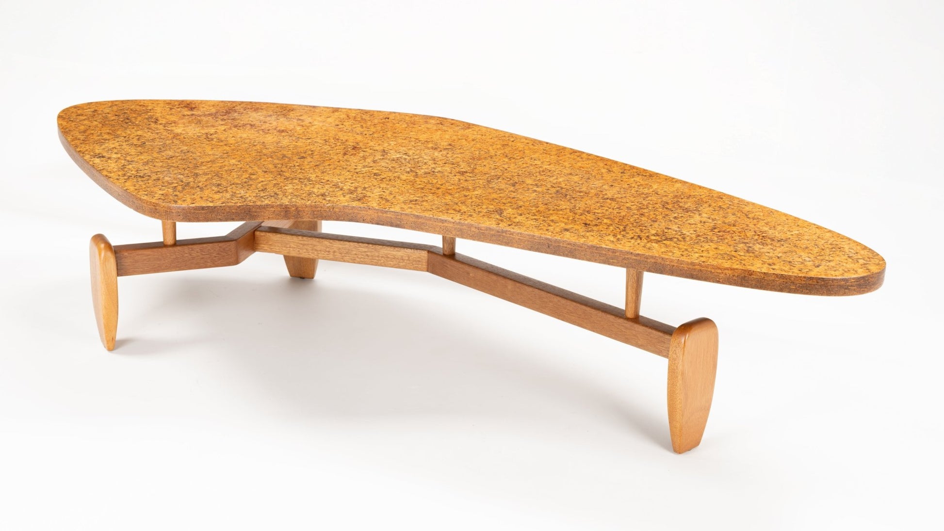 John Keal 'Outrigger' Coffee Table with a tapered asymmetrical cork tabletop resting on a streamlined wooden base featuring low-profile legs, illustrating mid century modern furniture design.