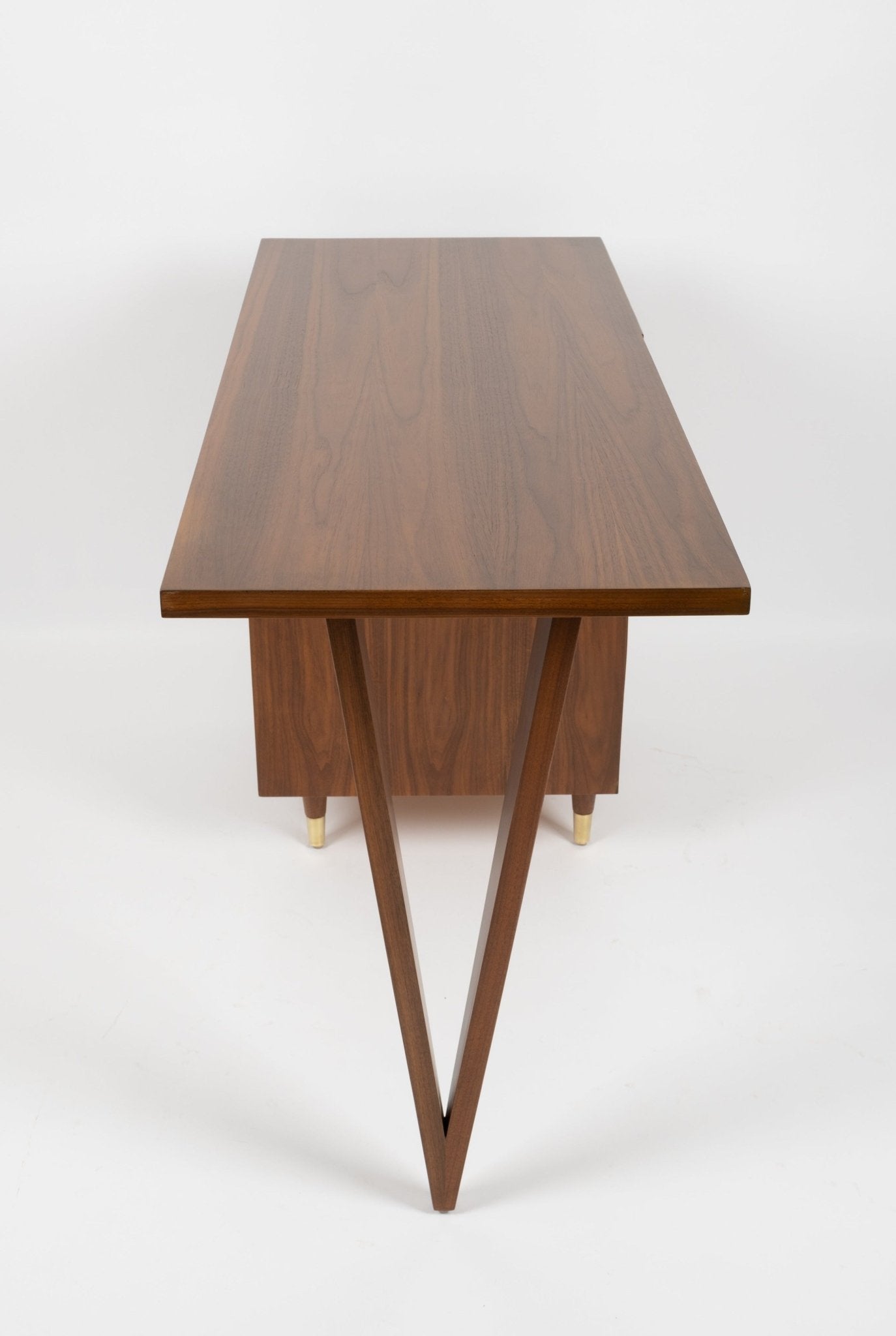 Mid-century modern John Stuart desk with triangular tapered legs, three-drawer cabinet, brass handles, and brass feet.