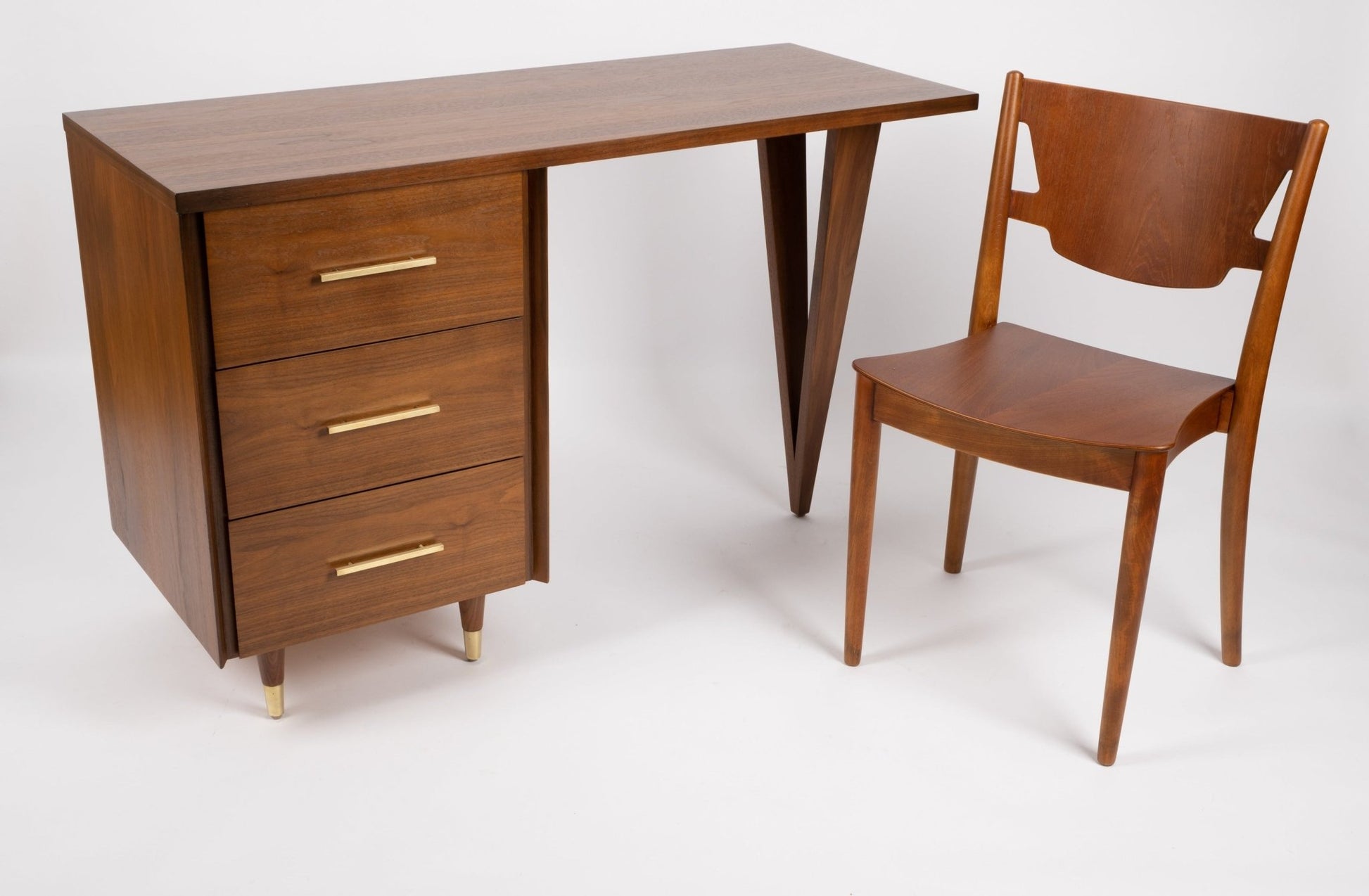 John Stuart mid-century modern desk with triangular legs, three drawers with brass handles, paired with wooden chair