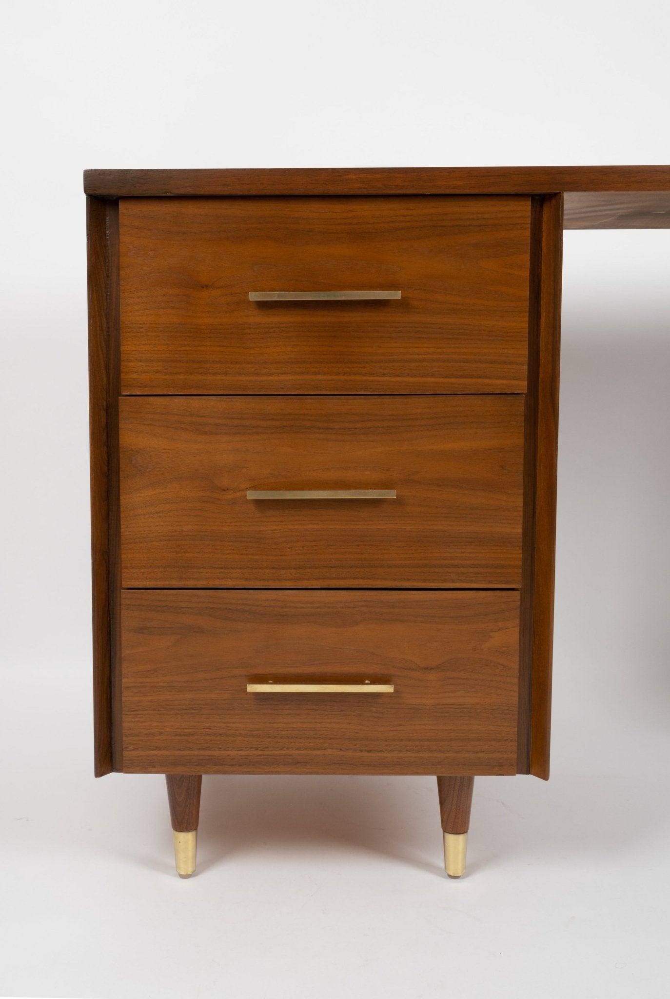 Mid-century modern wooden desk drawer unit with brass handles and tapered legs with brass feet in warm walnut finish.