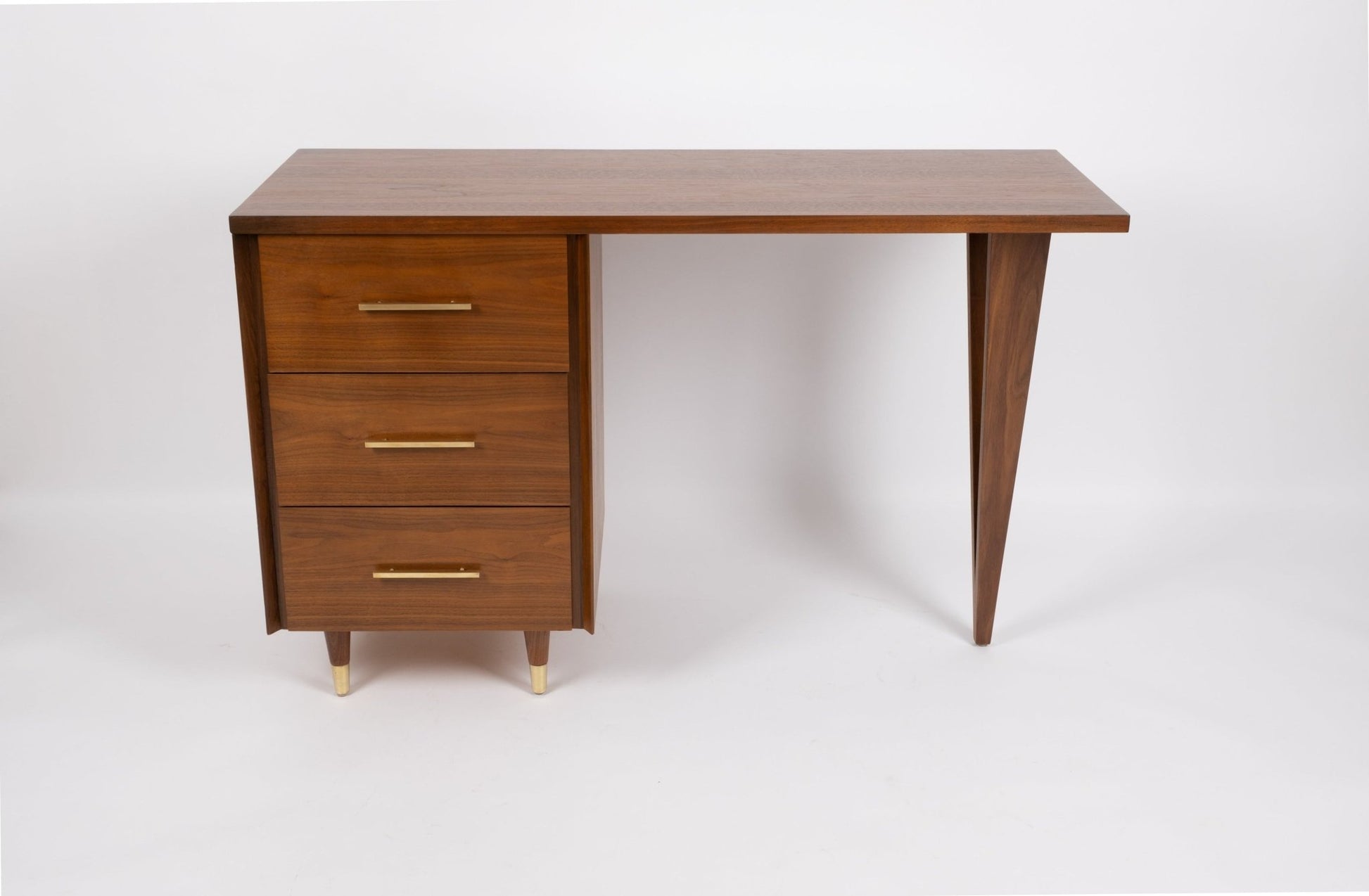 Mid-century modern John Stuart desk with triangular tapered legs, three drawers with brass handles and feet in wood finish