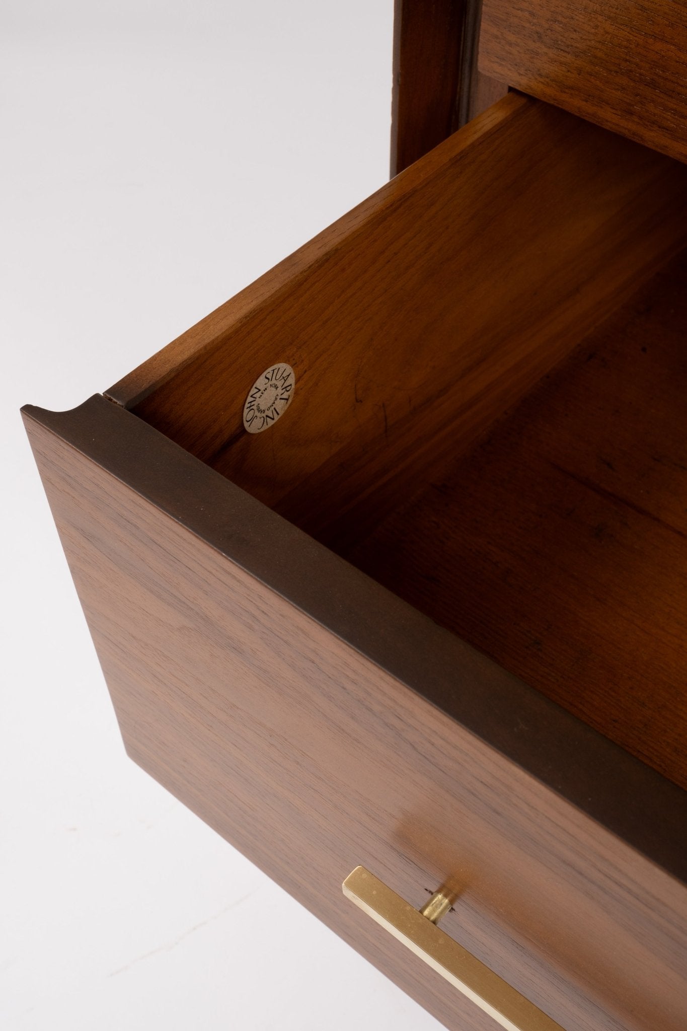 Open drawer of mid-century modern wooden desk featuring brass handle and smooth walnut finish