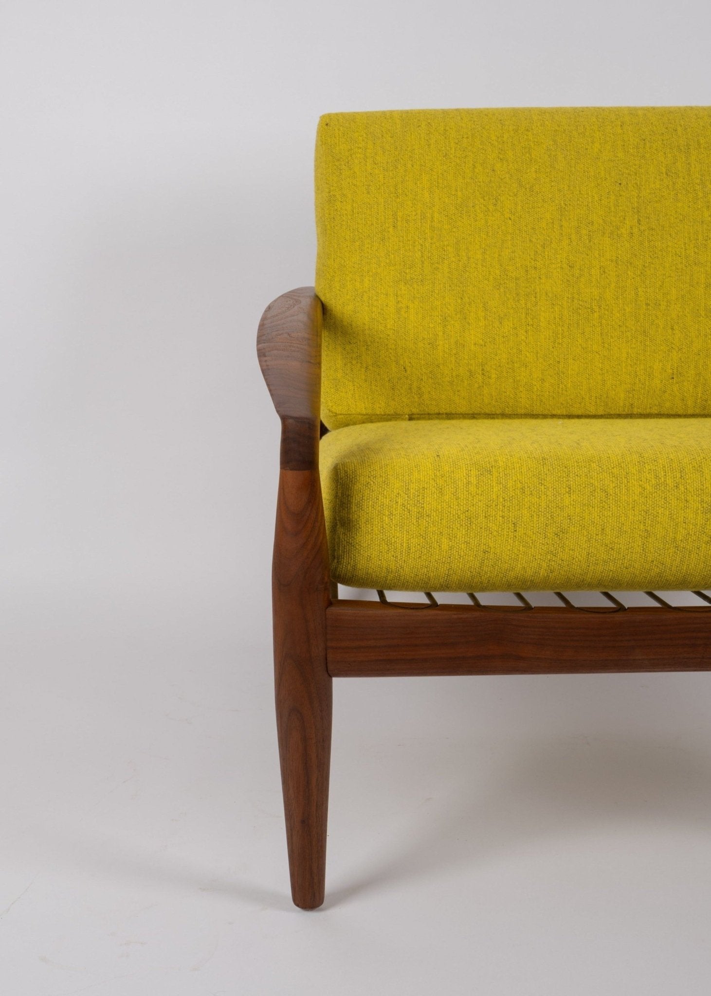 Close-up of teak frame and yellow upholstery on Kai Kristiansen 'Paper Knife' chair from 1950s Denmark.