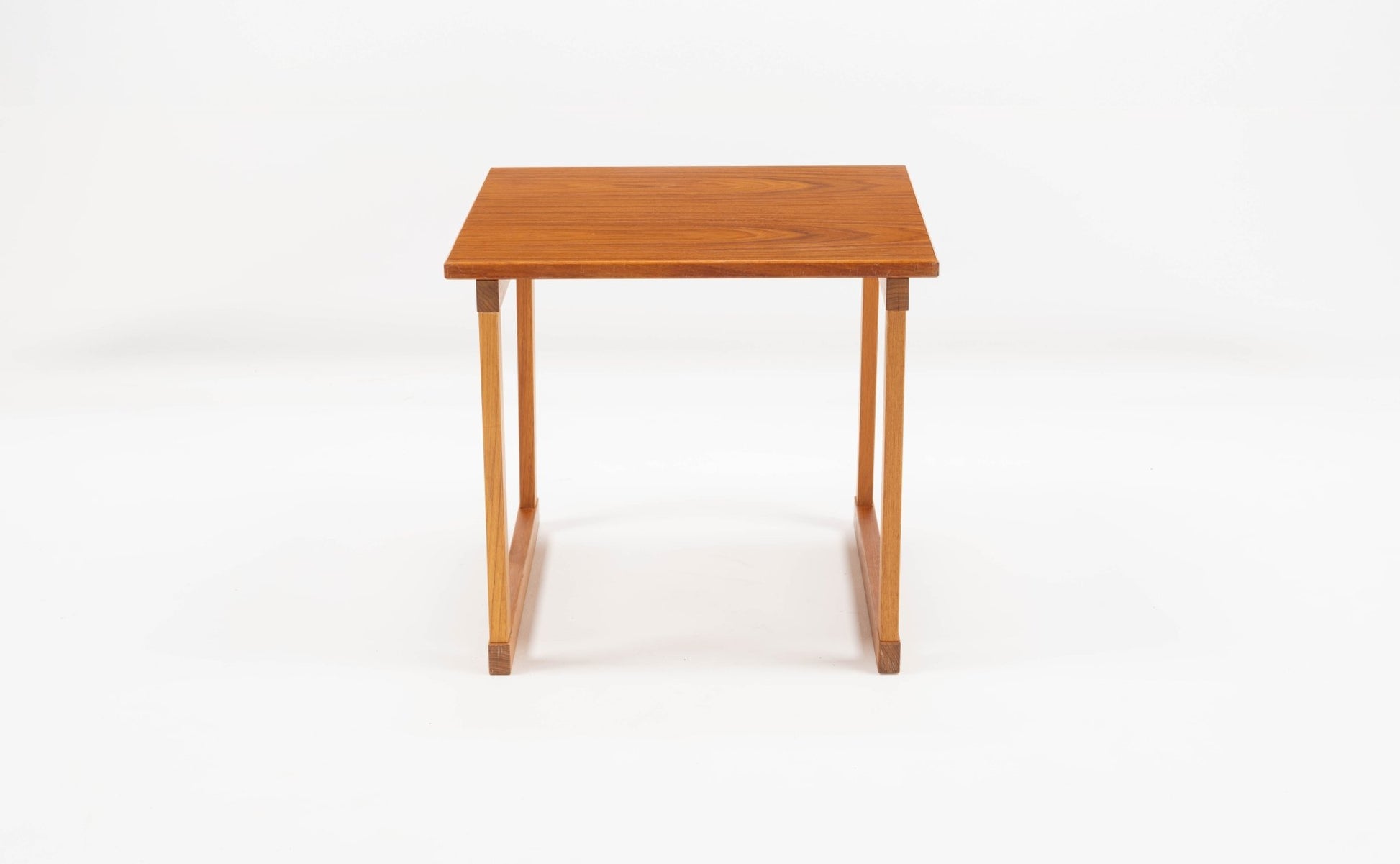 Mid-century modern teak side table with square top and interlocking leg design on white background