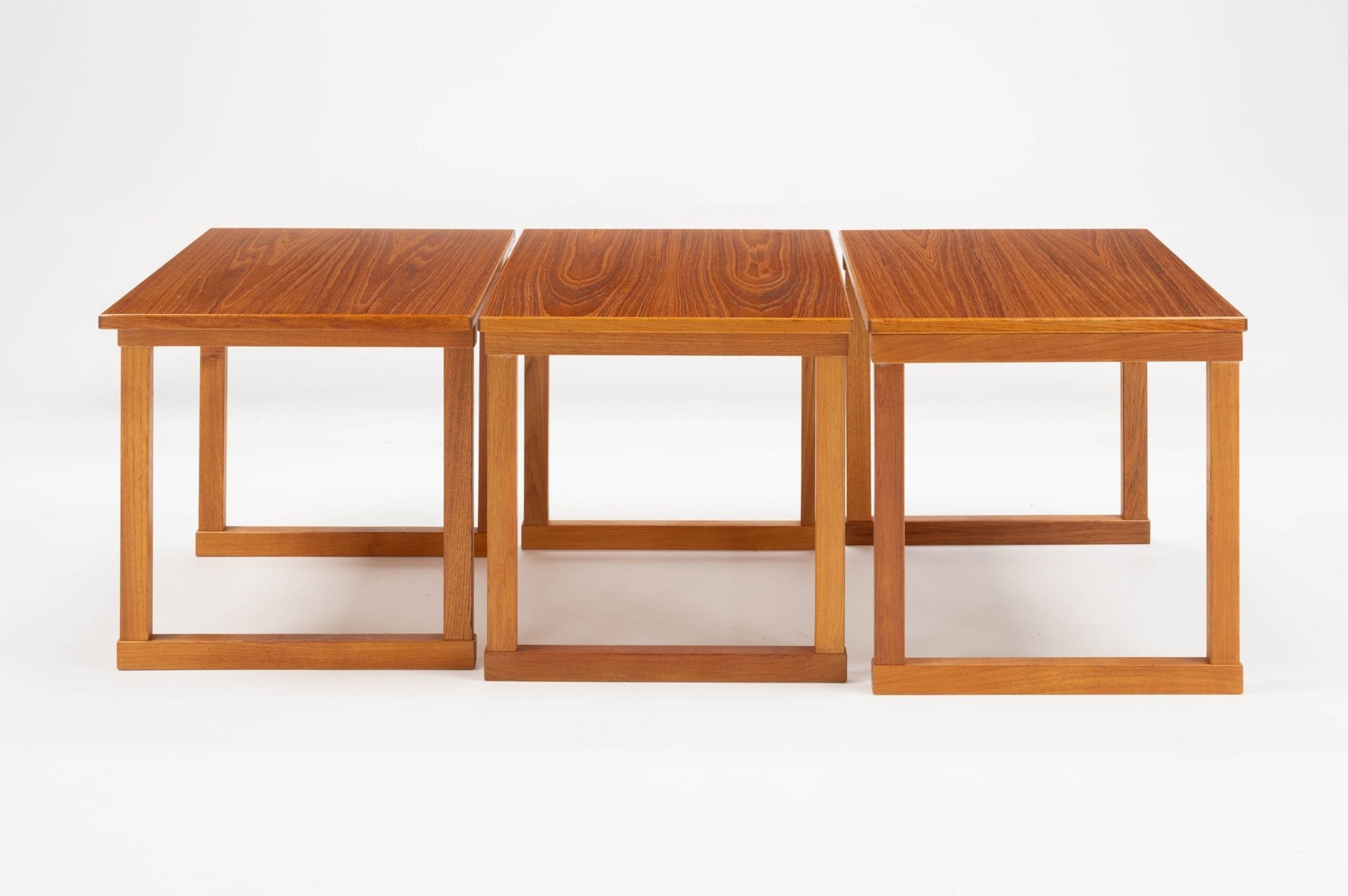 Set of three Kai Kristiansen "The Cube" teak interlocking side tables from 1960s Denmark on white background.