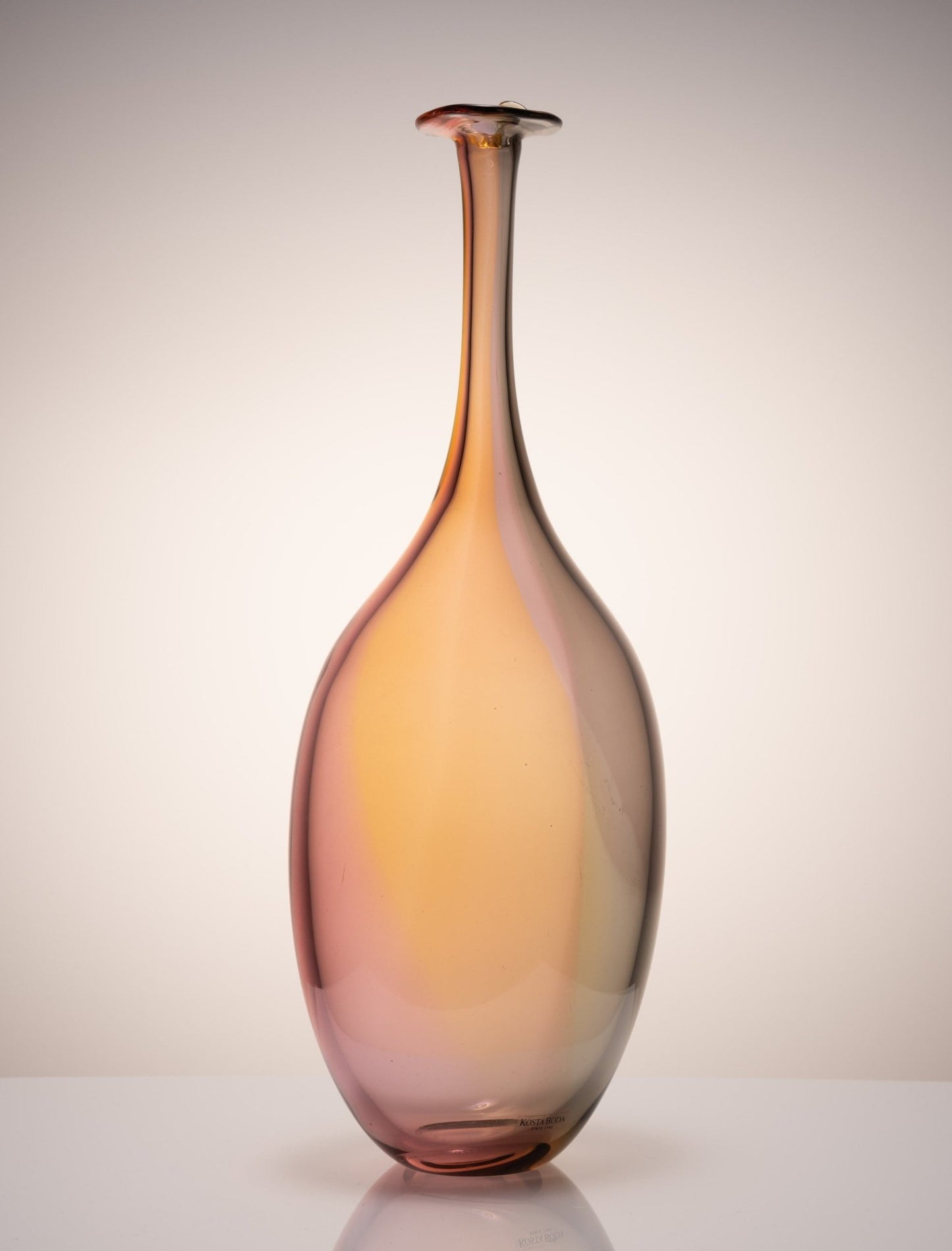 Kosta Boda Fidji glass bottle by Engman with elongated neck and gradient amber-pink color from Swedish artist collection