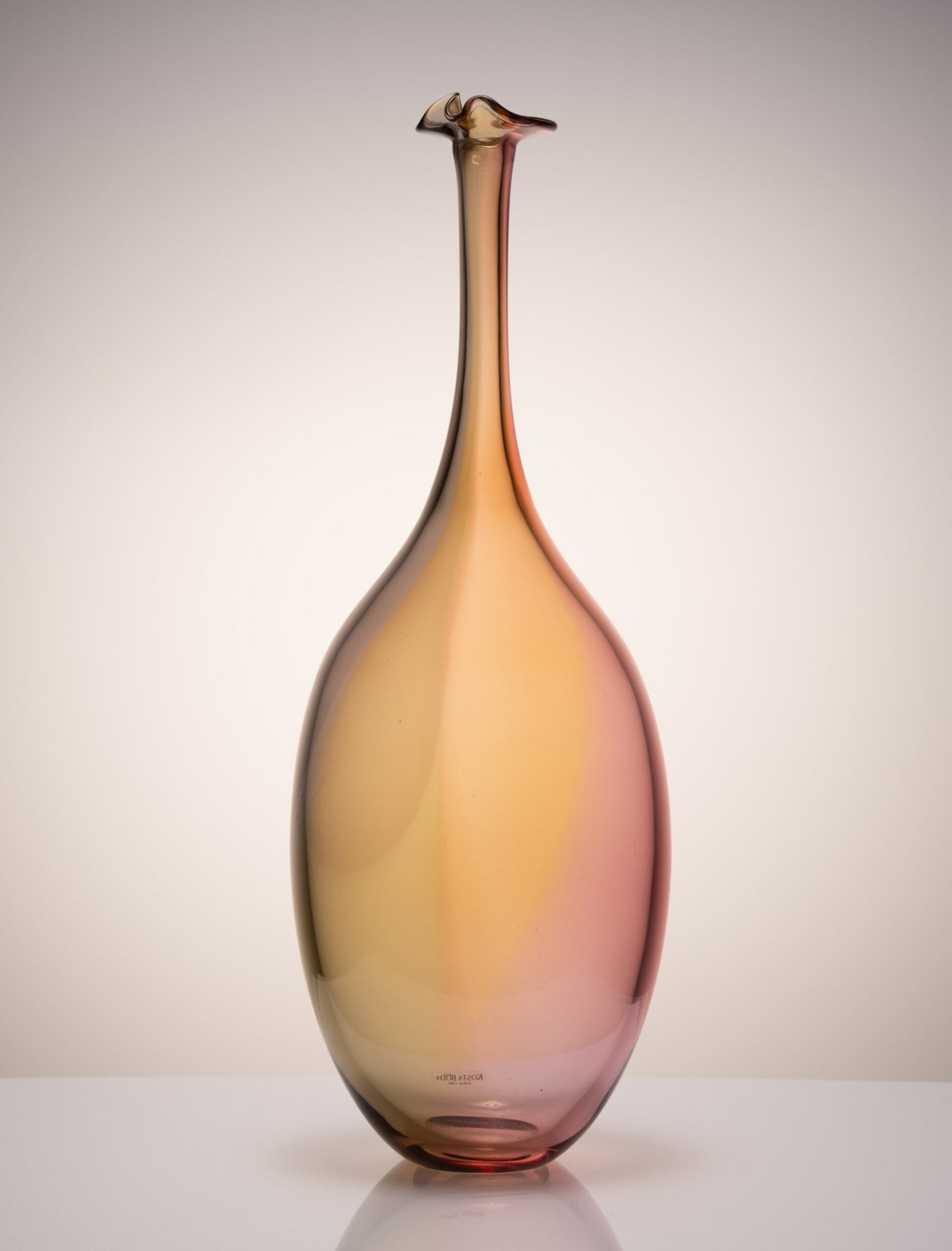 Kosta Boda Fidji glass bottle by Kjell Engman with elongated neck and gradient amber to pink hues from Sweden.