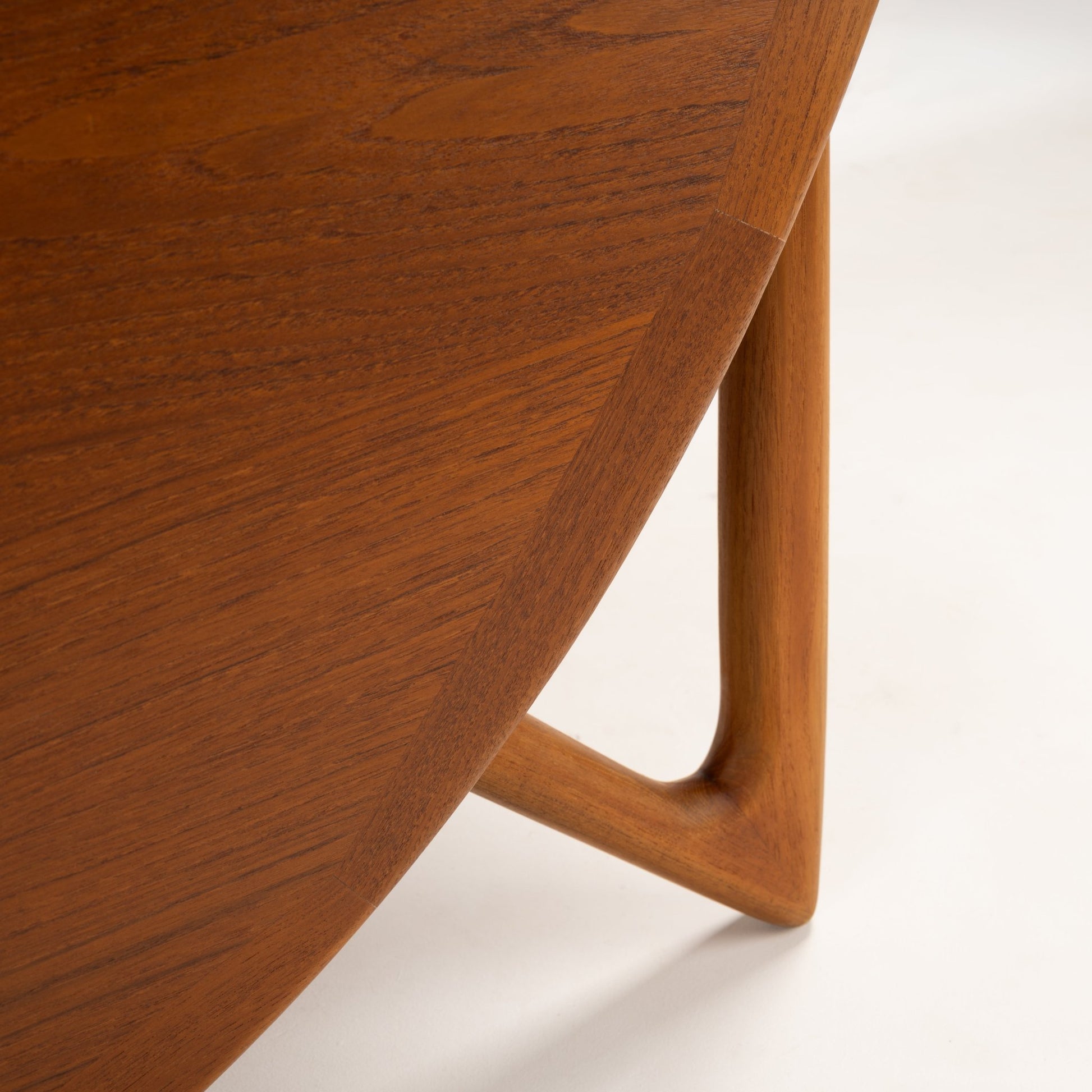 Kurt Ostervig Drop-Leaf Dining Table close view of curved walnut tabletop edge and sculptural tapered leg with warm grain in mid century modern furniture style