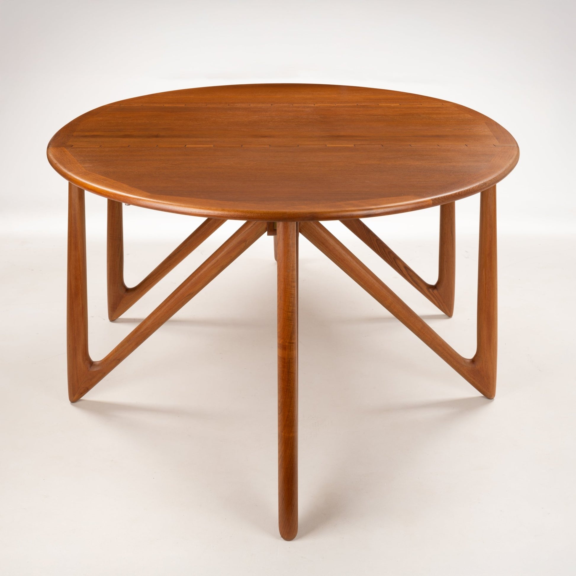 Kurt Ostervig Drop-Leaf Dining Table with oval wood top sculptural angled supports and warm polished grain in mid century modern furniture style