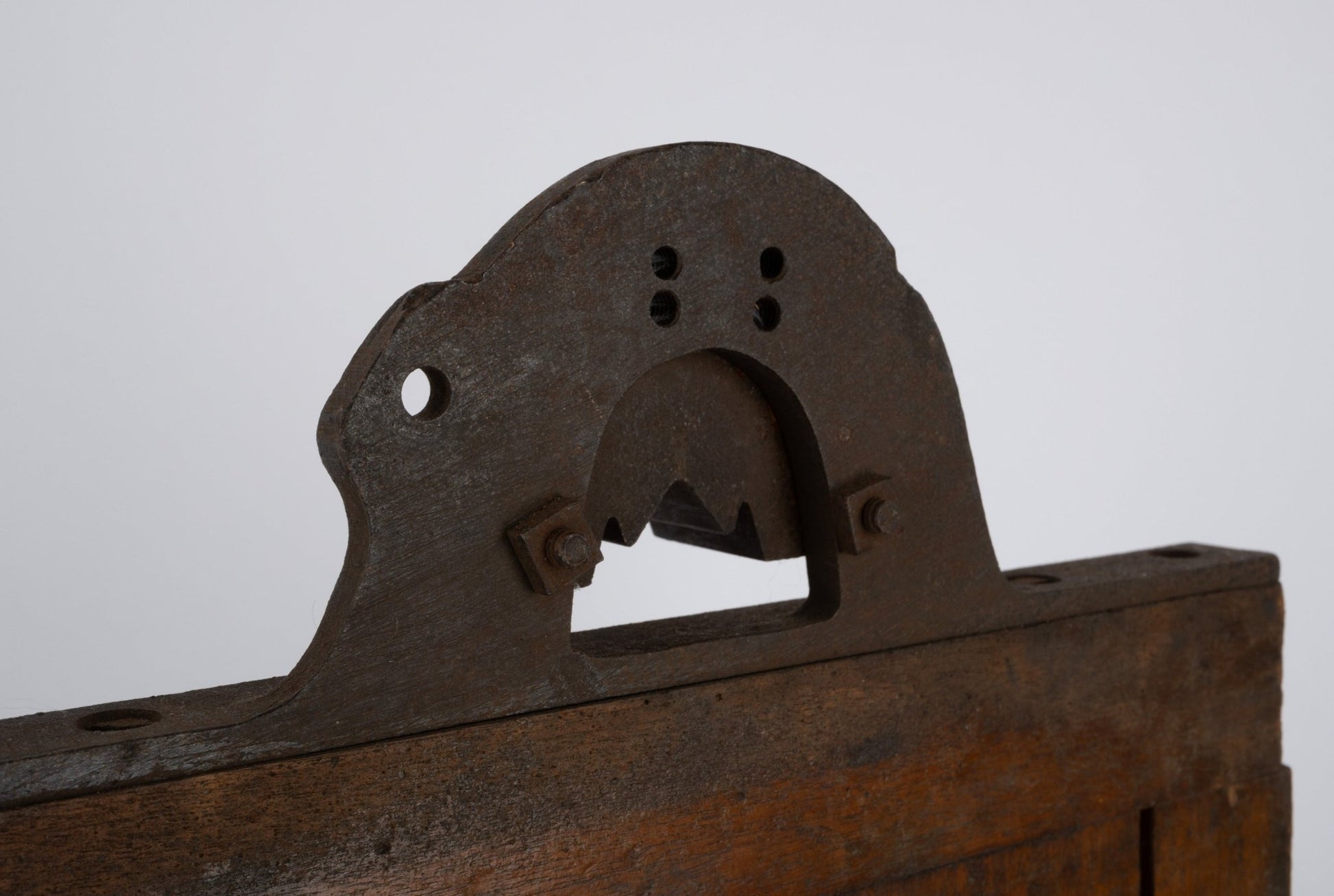 Two-sided wooden industrial machine mold with metal handle and rustic patina on white background.