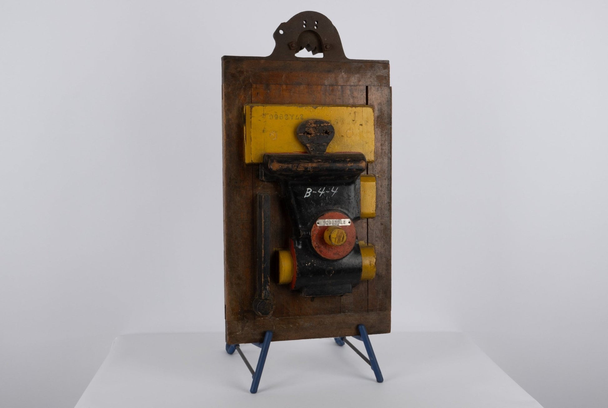 Two-sided vintage wooden industrial machine mold with metal handle and vibrant patina on display stand