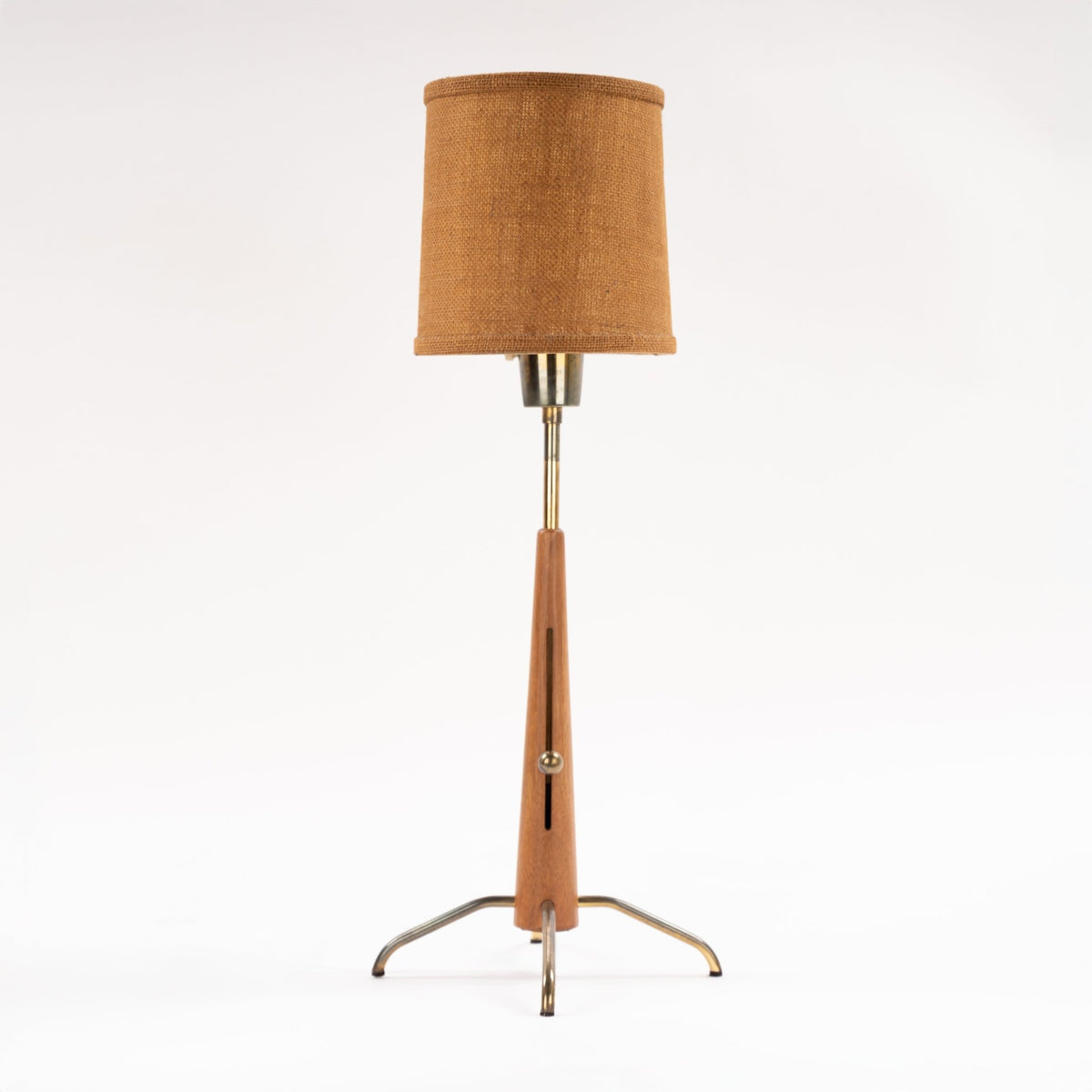 Manner of Josef Frank Table Lamp with tapered wood stem linen drum shade and polished metal tripod legs in mid century modern lighting