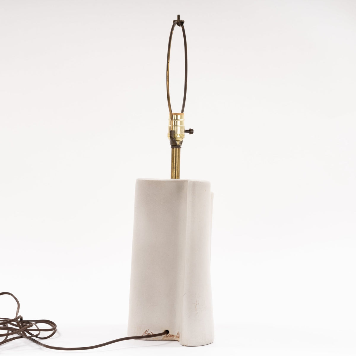 Marianna Von Allesch Table Lamp with a tall white ceramic base brass stem exposed socket and looped cord in minimalist mid century modern lighting