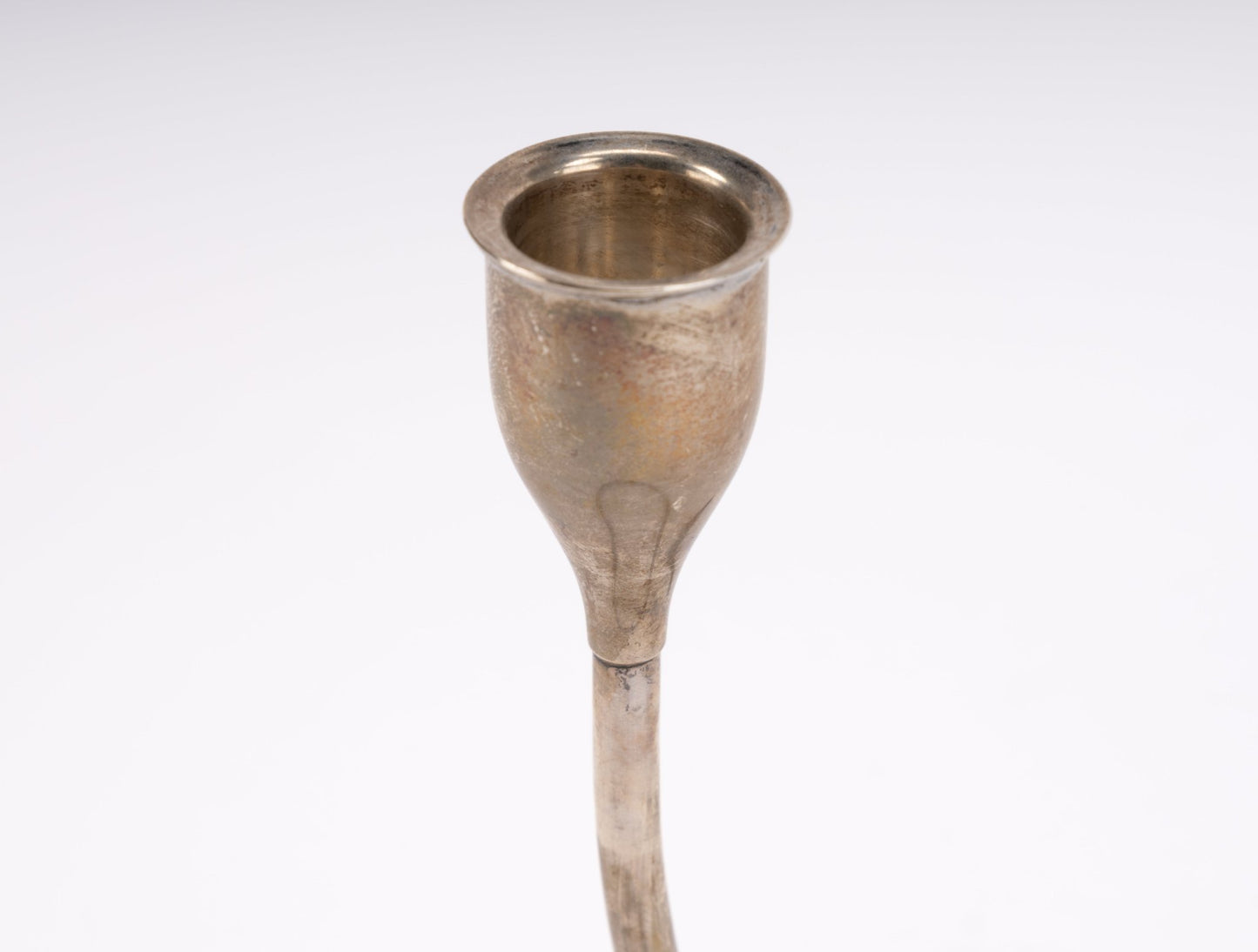 Close-up of mid-century sterling silver candlestick cup with smooth finish and plastic tip detail on white background